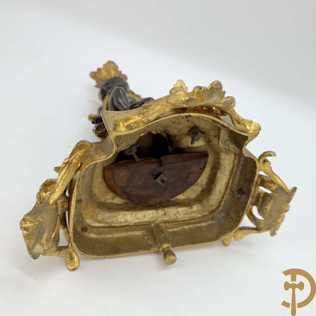 Driedelige bronzen garnituur bestaande uit middenstuk met bronzen vuurvergulde klok, Daubrée gemerkt à Nancy, bovenaan bekroond met Cleopatra met drinkbeker - getekend van Cumberworth sculpteur - geflankeerd door paar cupido