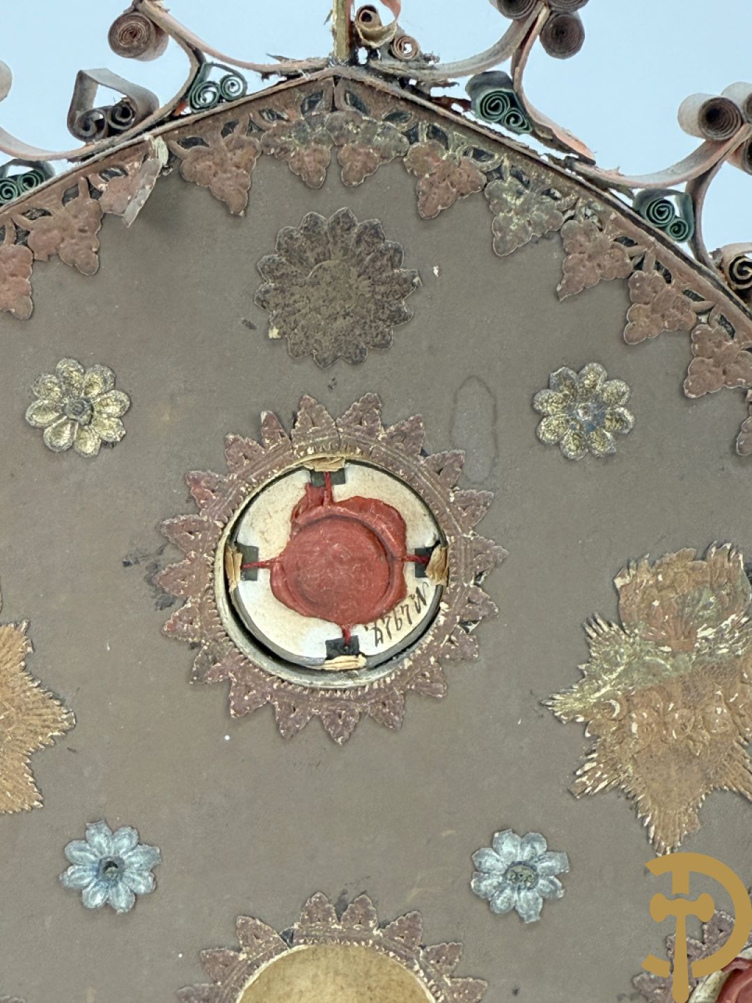 Relikwiehouder in de vorm van een altaar met Christusnagel en omgeven door papperollen - onder stolp