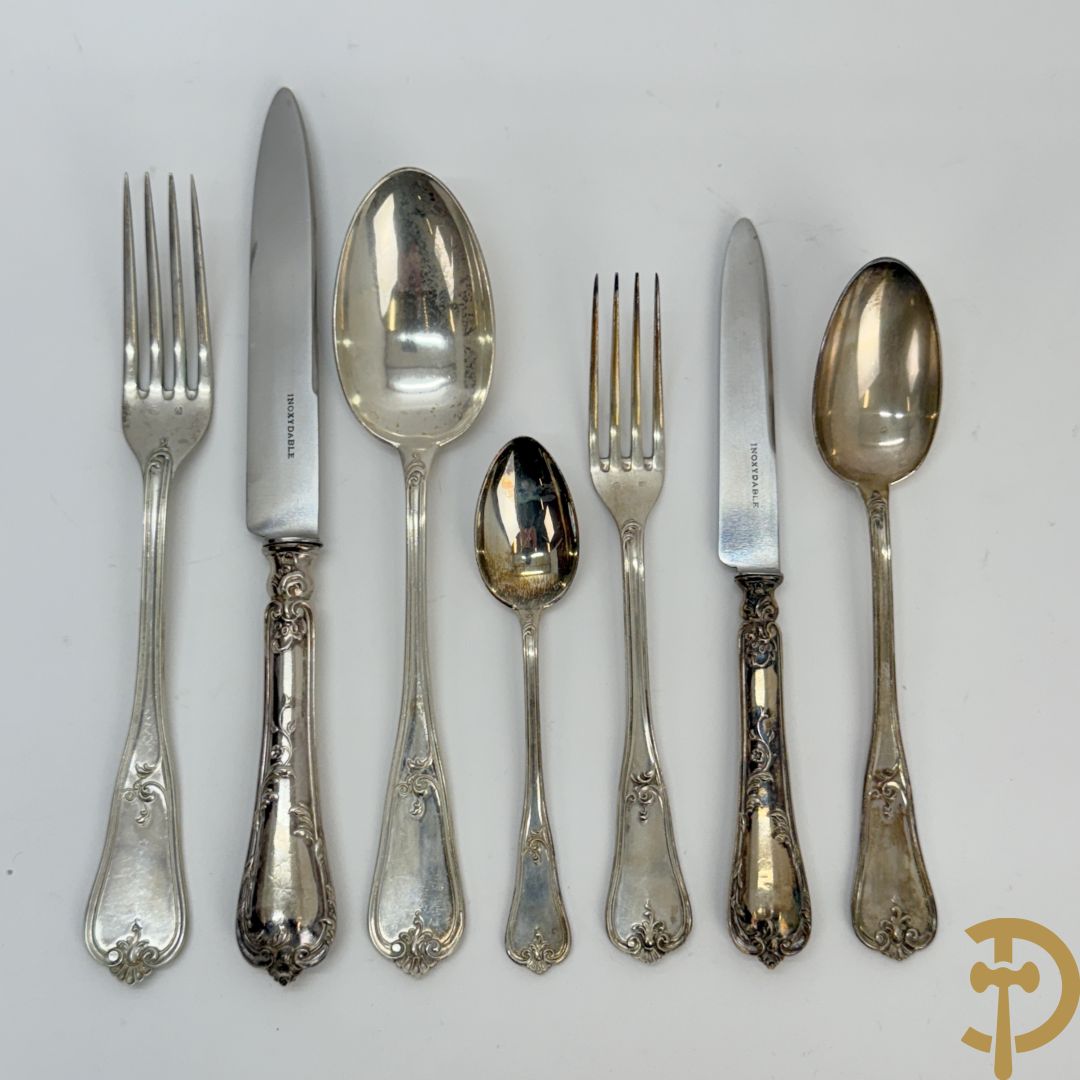 Massief zilveren bestek met Louis XV motieven bestaande uit 12 soeplepels (72 gram per stuk), 12 vorken (78 gram per stuk), 12 messen, 12 dessertvorken (47 gram per stuk), 12 dessertlepels (40 gram per stuk), 12 dessertmessen, 12 koffielepels (22 gram per stuk), slacouvert, taartschep en suikertang