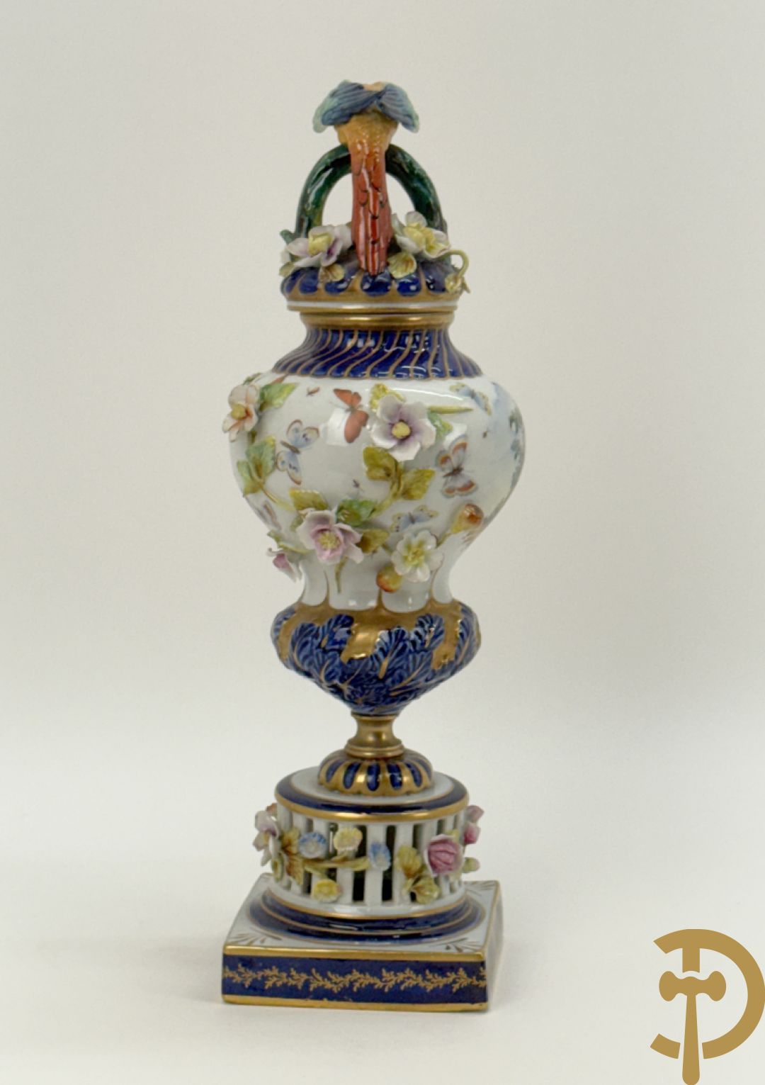 Porseleinen siervaas met handbeschilderd geanimeerd decor bezet met basrelief van bloemen en bovenaan bekroond met deksel met vogel