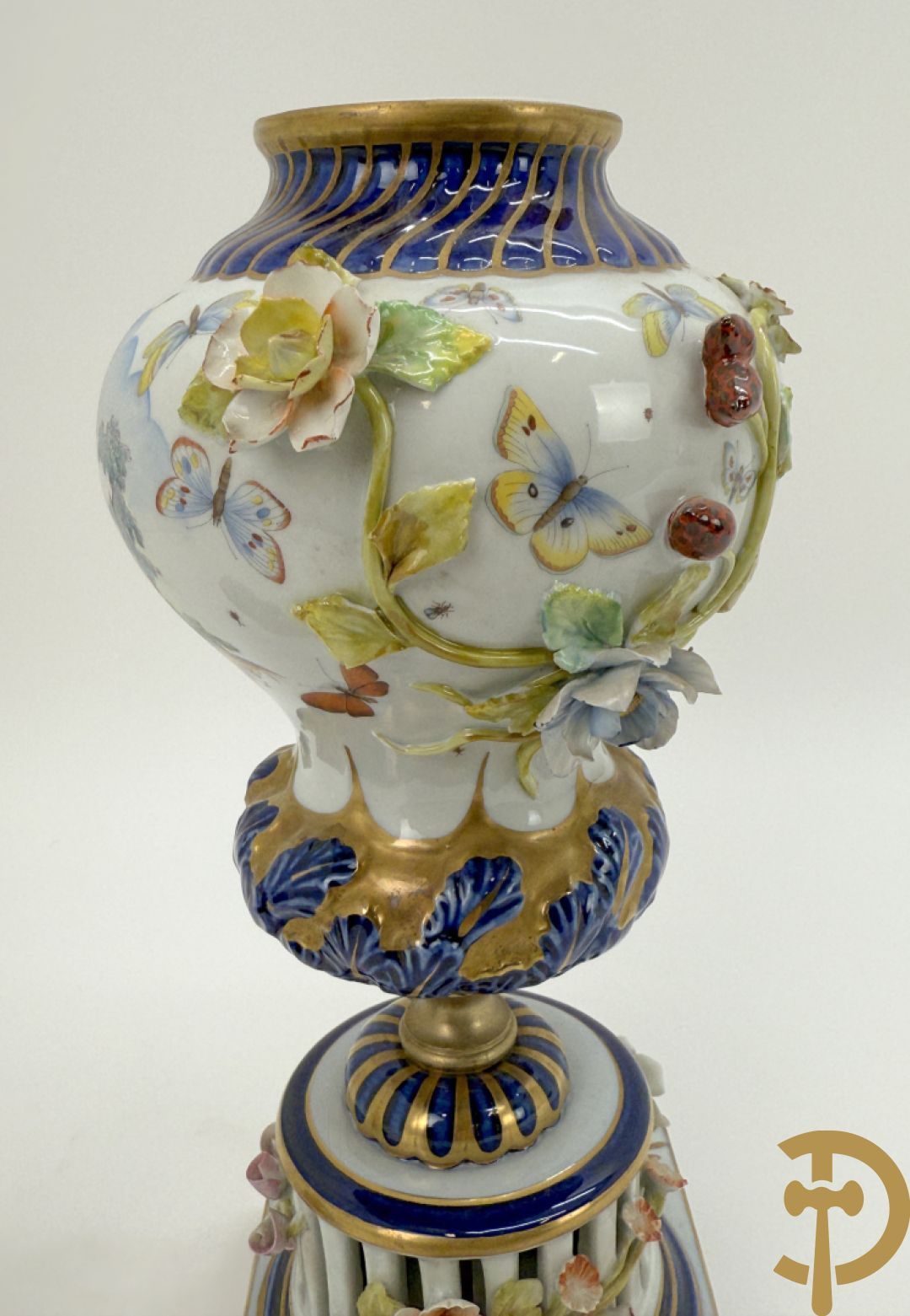 Porseleinen siervaas met handbeschilderd geanimeerd decor bezet met basrelief van bloemen en bovenaan bekroond met deksel met vogel