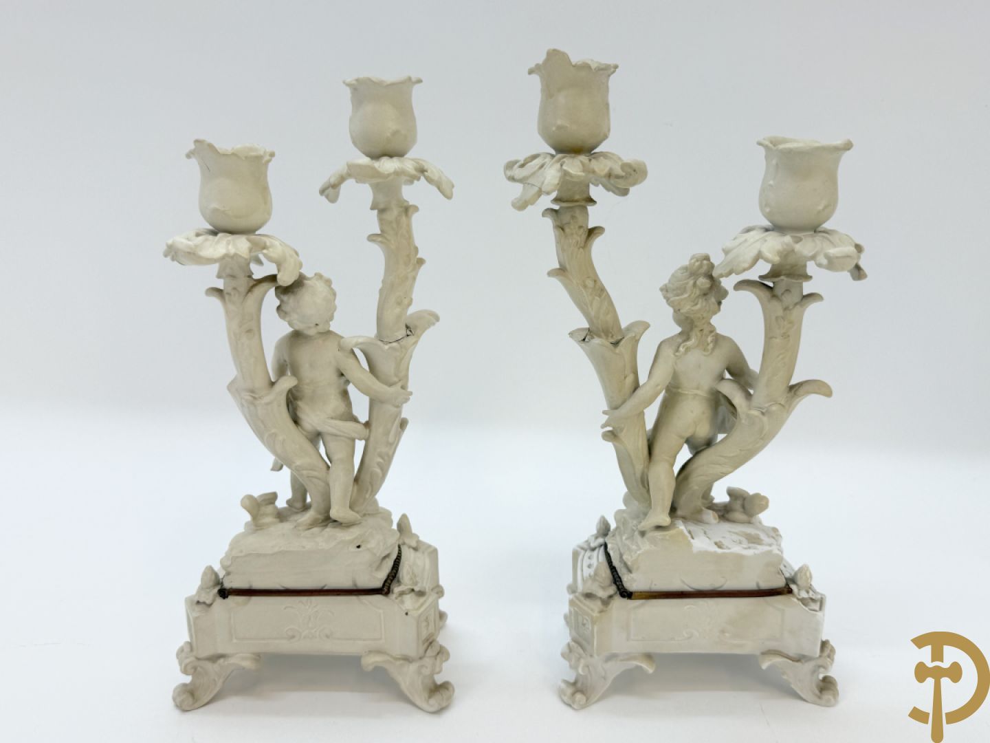 Driedelige porseleinen garnituur bestaande uit pendule bezet met lieftallig koppel, geflankeerd door paar kandelaars met cupido