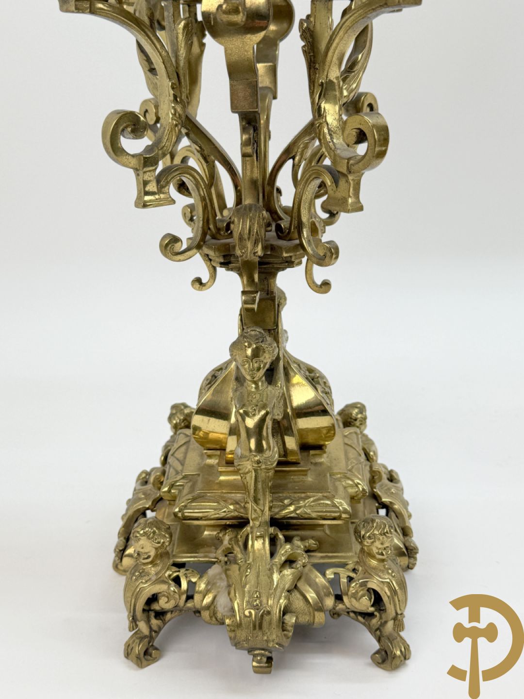 Driedelige bronzen vergulde garntiuur bestaande uit klok met medusahoofden en sfinxen, geflankeerd door paar zevenarmige kandelaars met accanthusranken en sfinxen