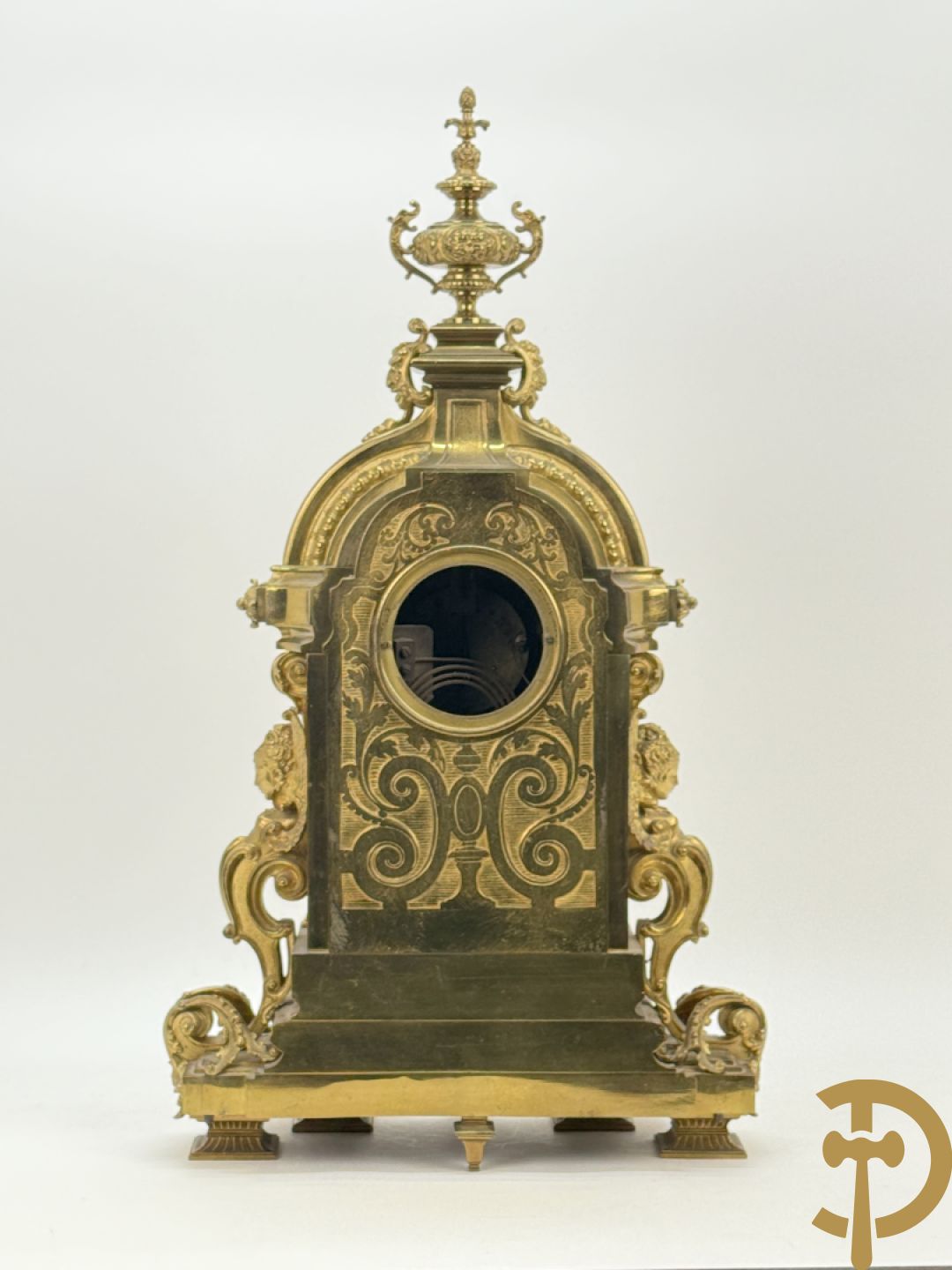 Vuurvergulde bronzen pendule, zijdelings bezet met gevleugelde dames, bovenaan met amfoor