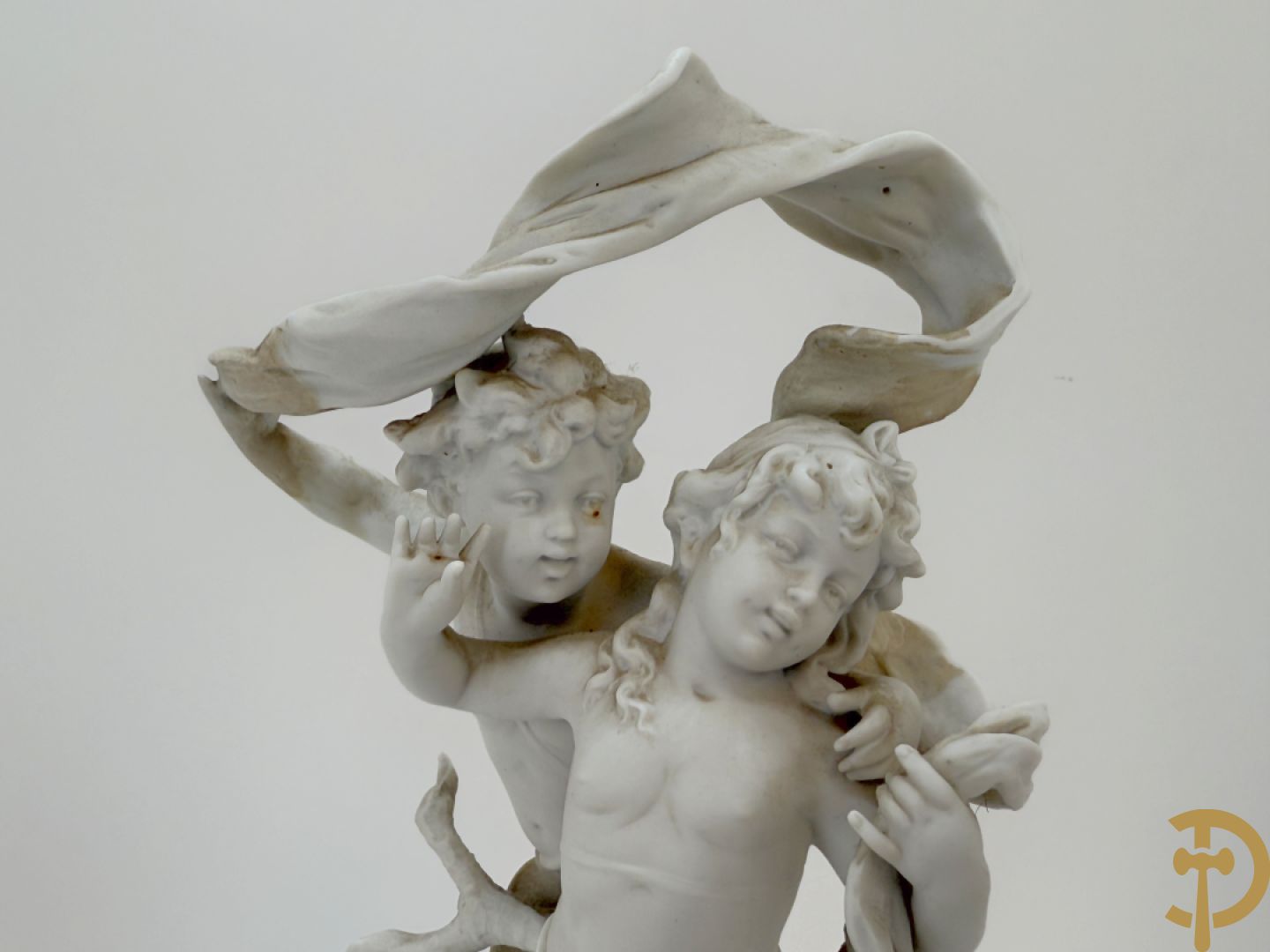 Driedelige porseleinen garnituur bestaande uit pendule bezet met lieftallig koppel, geflankeerd door paar kandelaars met cupido