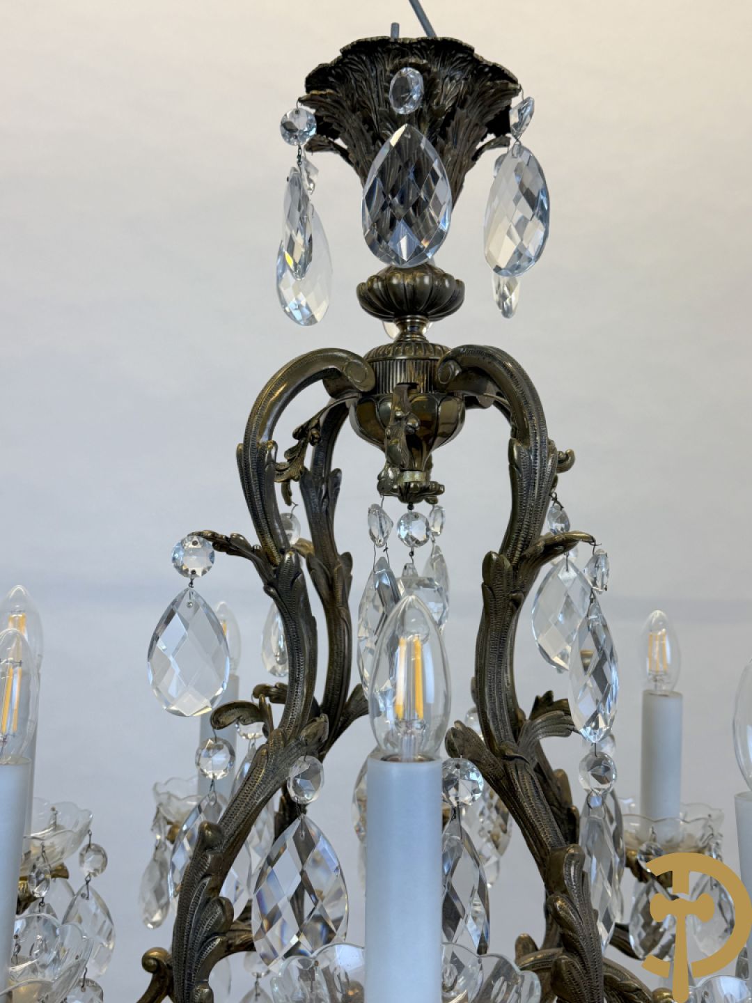 Achtarmige koperen luchter met kristallen bellen en binnenin met pinakel bezet