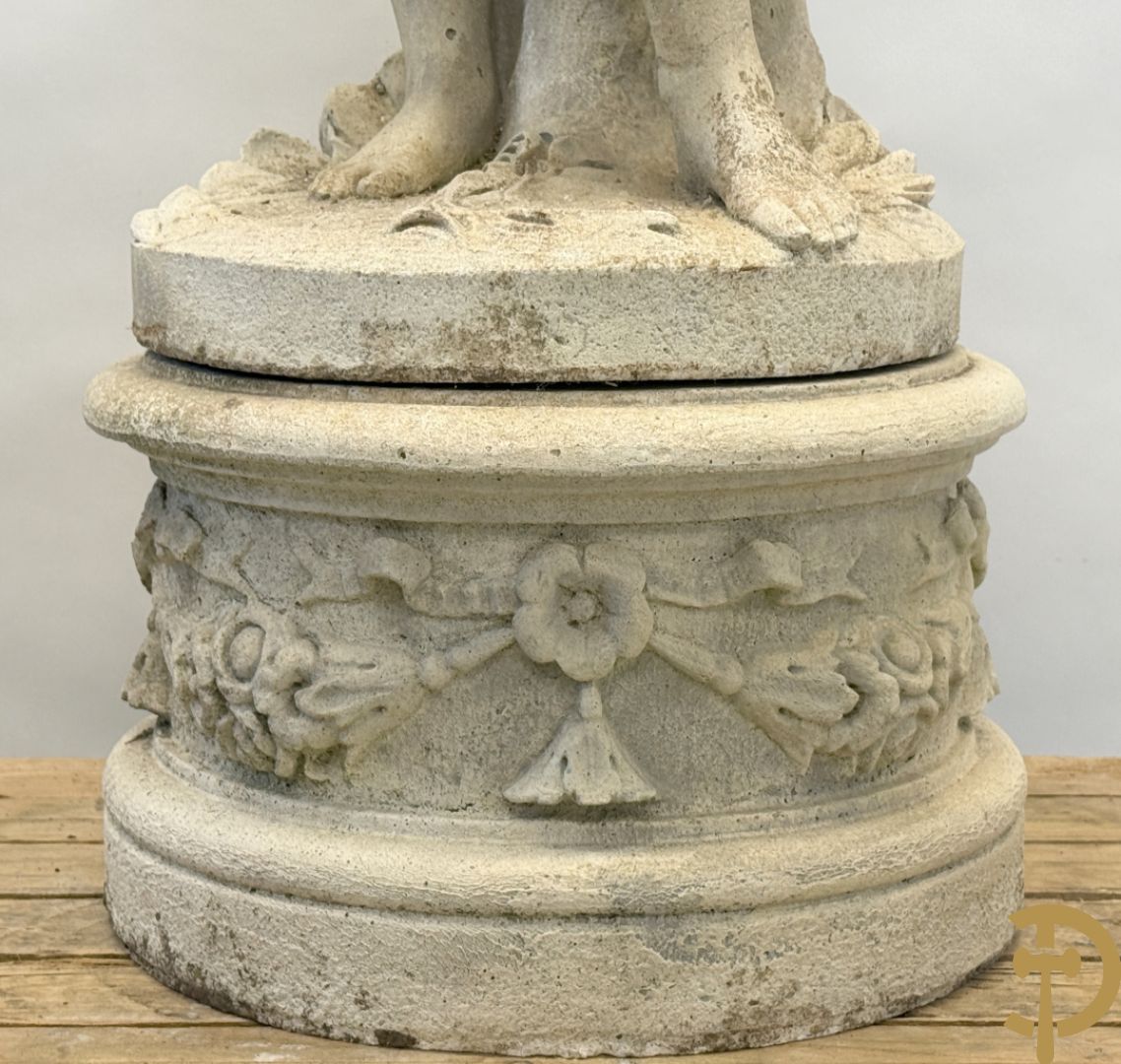 Stenen tuinbeeld van jongeman met mand in de hand op sokkel met guirlandes