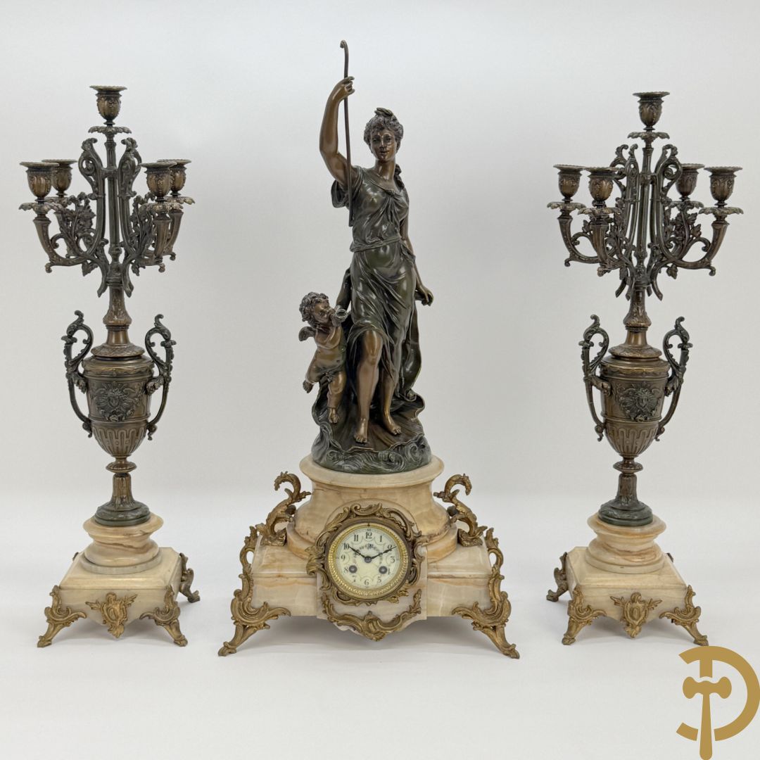Driedelige zamak garnituur bestaande uit pendule met cupido en dame geflankeerd door paar vijfarmige kandelaars, Bruchon getekend