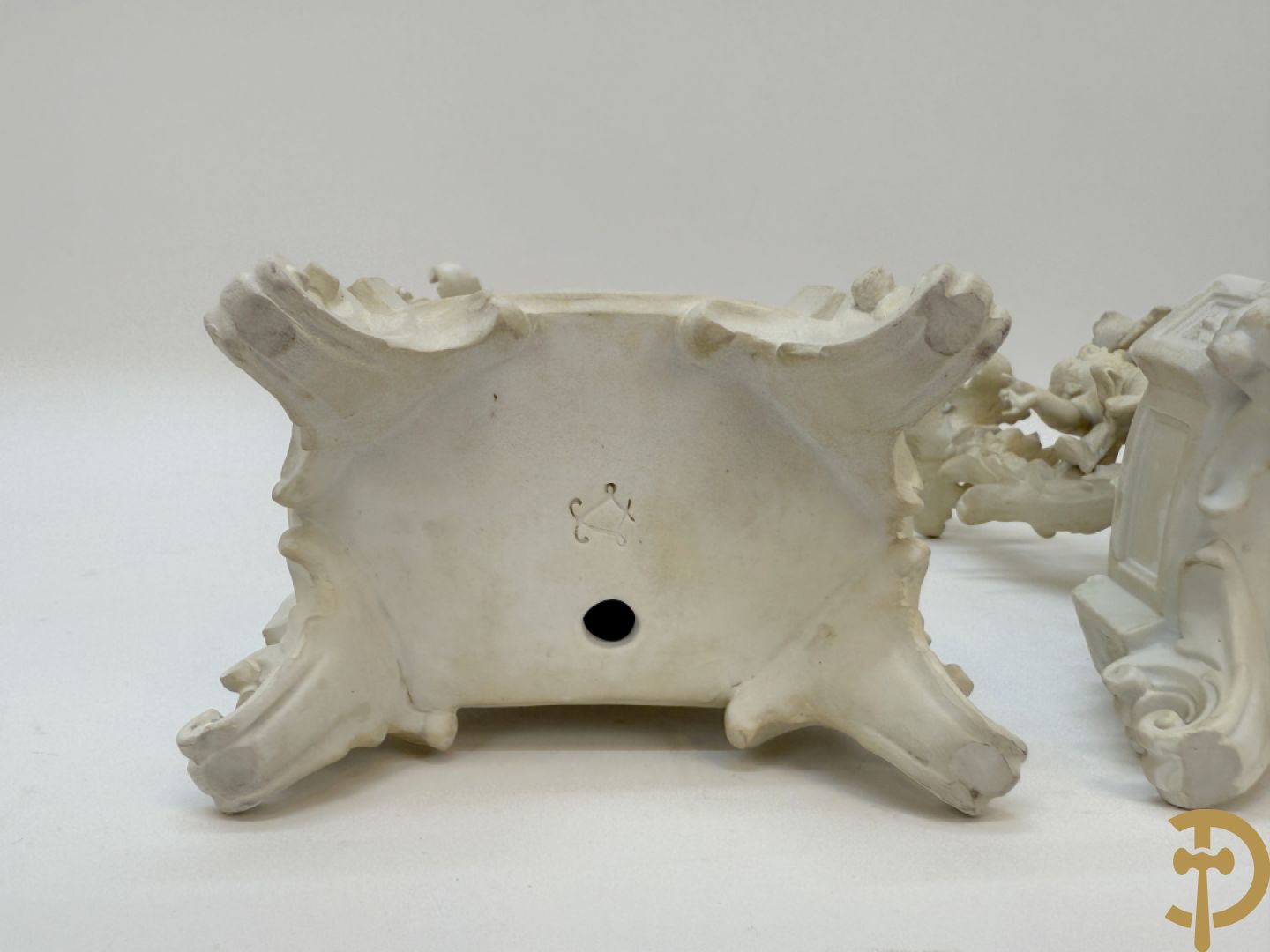 Driedelige porseleinen garnituur bestaande uit pendule bezet met lieftallig koppel, geflankeerd door paar kandelaars met cupido