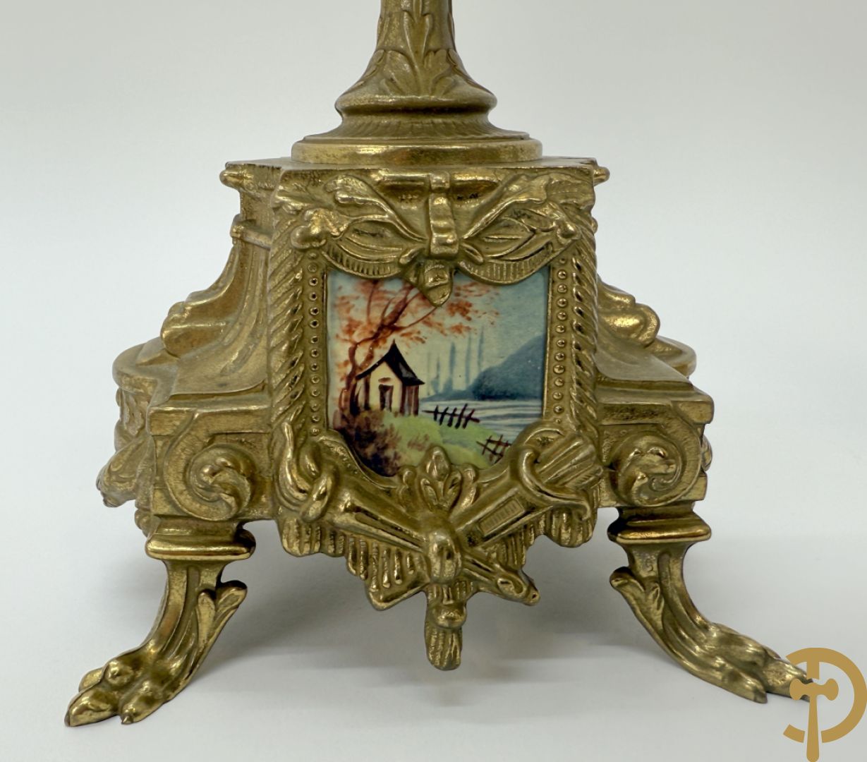 Driedelige koperen garnituur bestaande uit pendule met beschilderd romantisch tafereel en amfoor, zijdelings bezet met paar cassolettes met geanimeerde scènes, onleesbaar getekend rechts onder klok