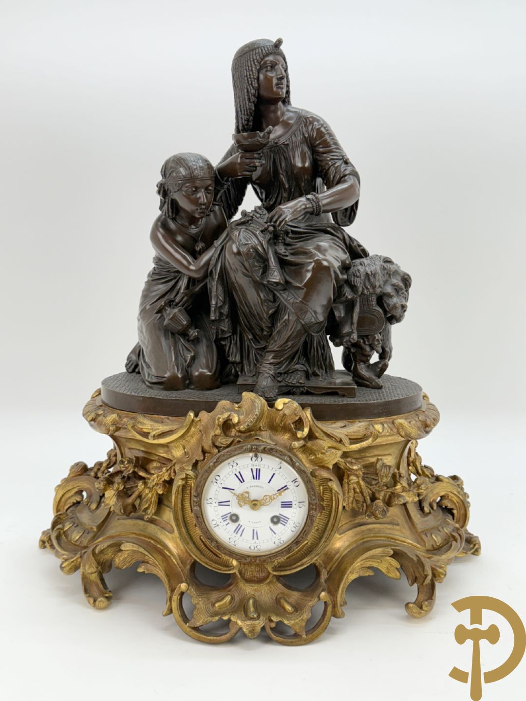 Driedelige bronzen garnituur bestaande uit middenstuk met bronzen vuurvergulde klok, Daubrée gemerkt à Nancy, bovenaan bekroond met Cleopatra met drinkbeker - getekend van Cumberworth sculpteur - geflankeerd door paar cupido