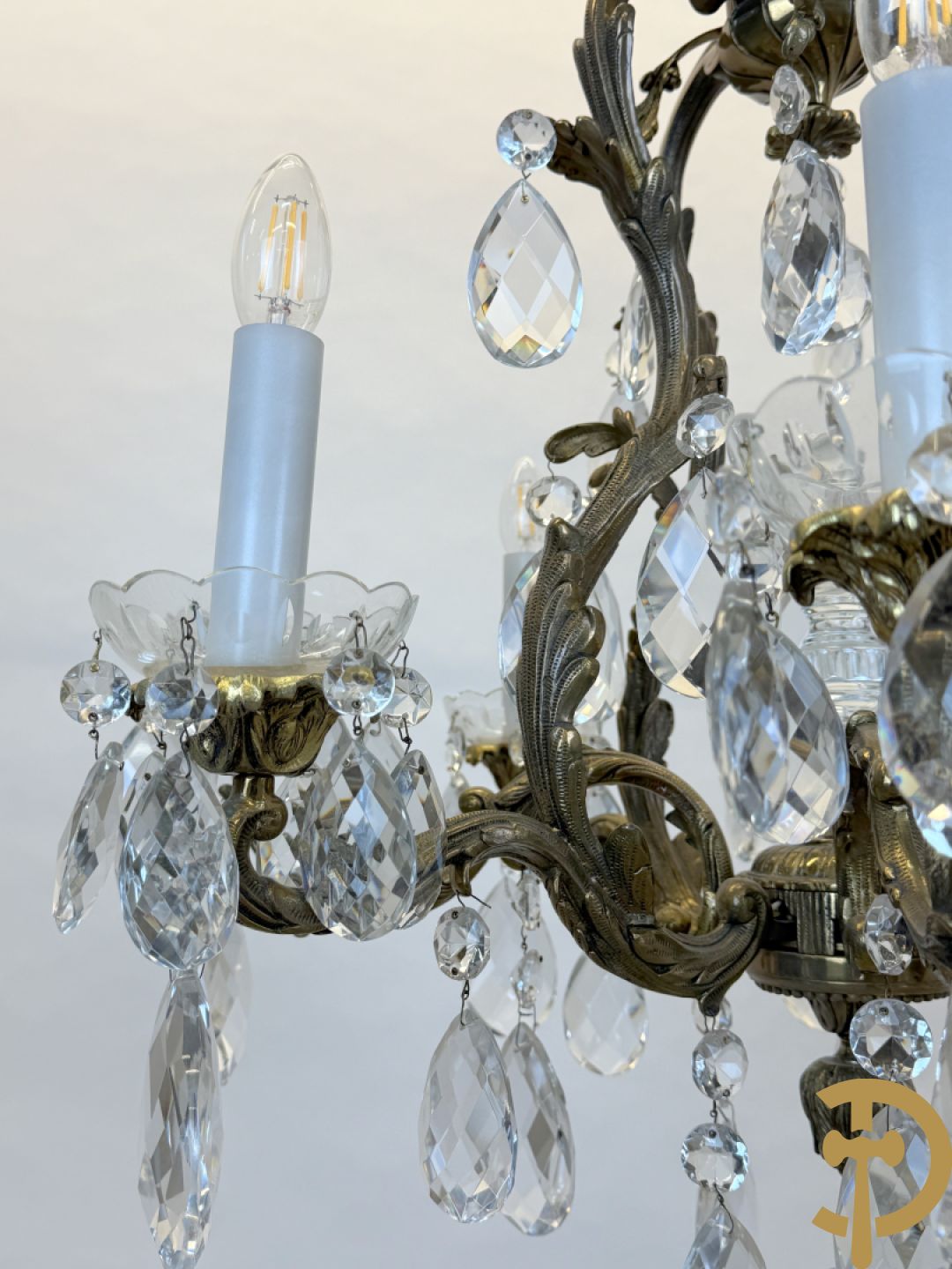 Achtarmige koperen luchter met kristallen bellen en binnenin met pinakel bezet