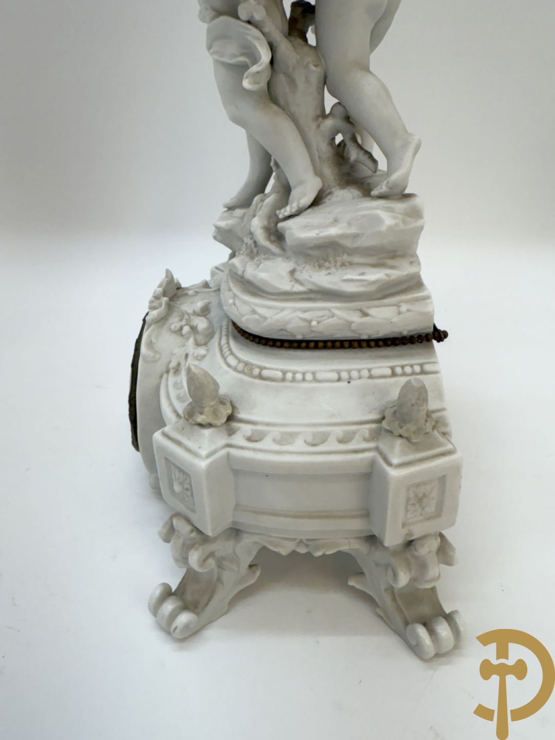 Driedelige porseleinen garnituur bestaande uit pendule bezet met lieftallig koppel, geflankeerd door paar kandelaars met cupido