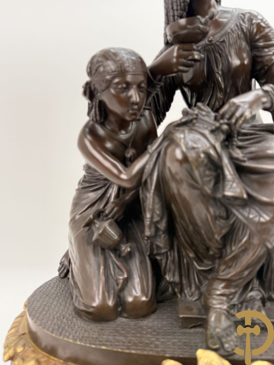 Driedelige bronzen garnituur bestaande uit middenstuk met bronzen vuurvergulde klok, Daubrée gemerkt à Nancy, bovenaan bekroond met Cleopatra met drinkbeker - getekend van Cumberworth sculpteur - geflankeerd door paar cupido