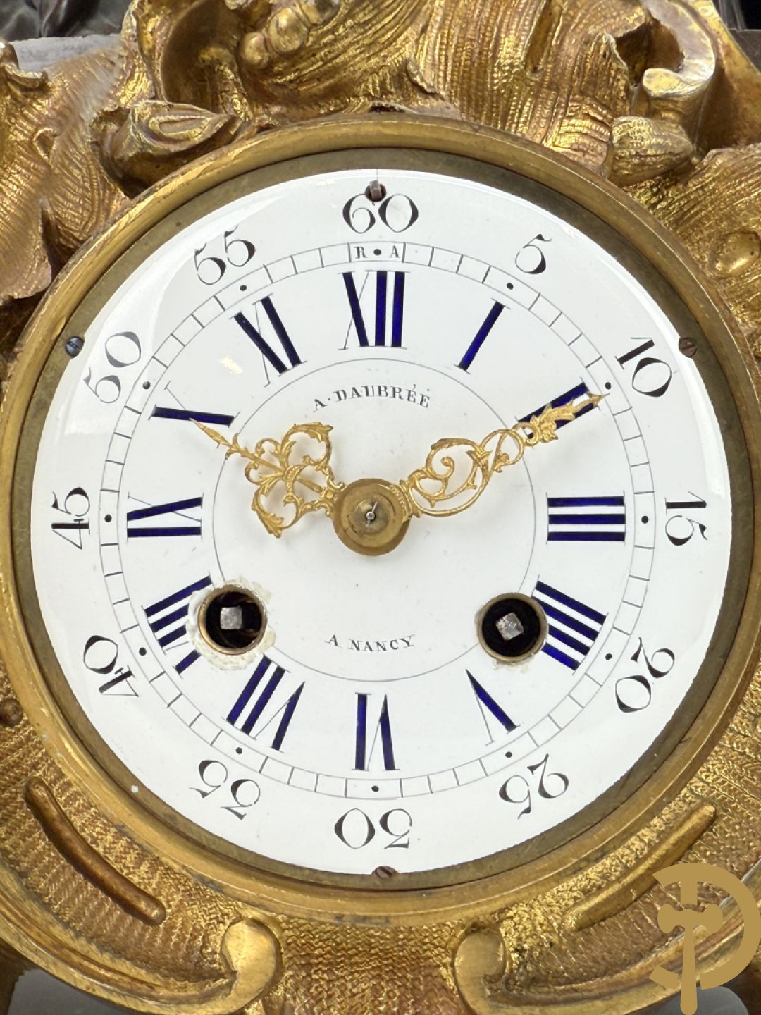 Driedelige bronzen garnituur bestaande uit middenstuk met bronzen vuurvergulde klok, Daubrée gemerkt à Nancy, bovenaan bekroond met Cleopatra met drinkbeker - getekend van Cumberworth sculpteur - geflankeerd door paar cupido