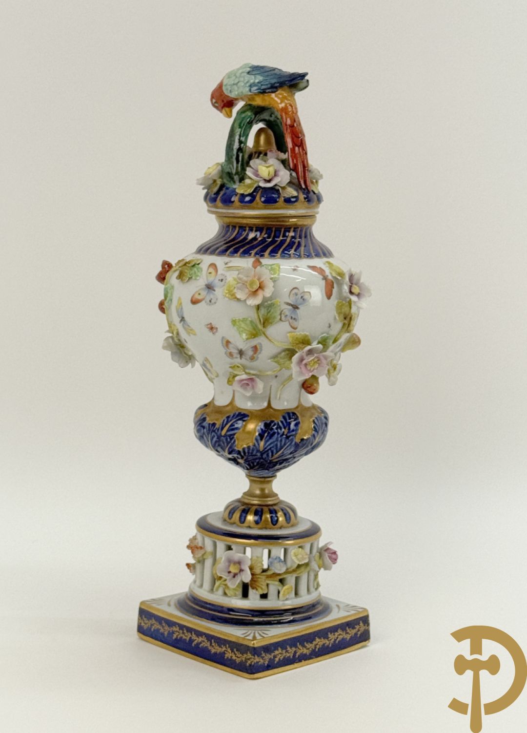 Porseleinen siervaas met handbeschilderd geanimeerd decor bezet met basrelief van bloemen en bovenaan bekroond met deksel met vogel