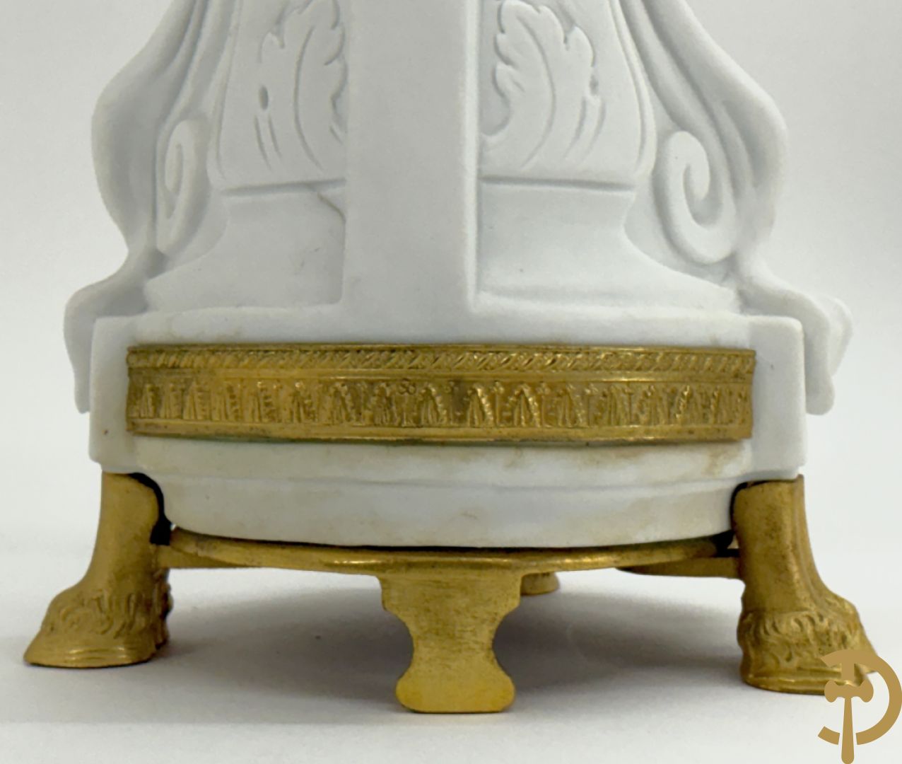 Driedelige porseleinen garnituur met bronsbeslag bestaande uit pendule met dame en amfoor geflankeerd door paar kandelaars bezet met personages