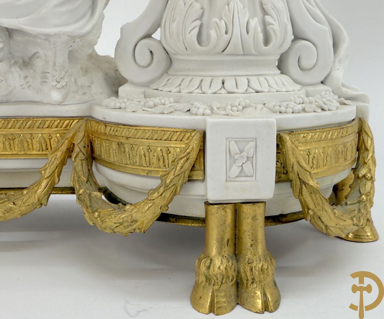 Driedelige porseleinen garnituur met bronsbeslag bestaande uit pendule met dame en amfoor geflankeerd door paar kandelaars bezet met personages