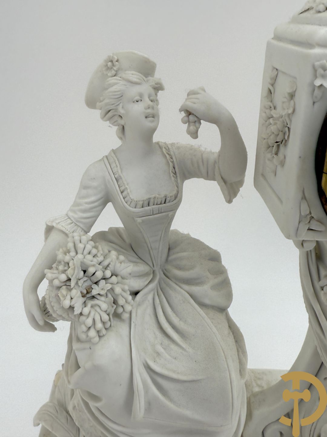 Driedelige porseleinen garnituur met bronsbeslag bestaande uit pendule met dame en amfoor geflankeerd door paar kandelaars bezet met personages