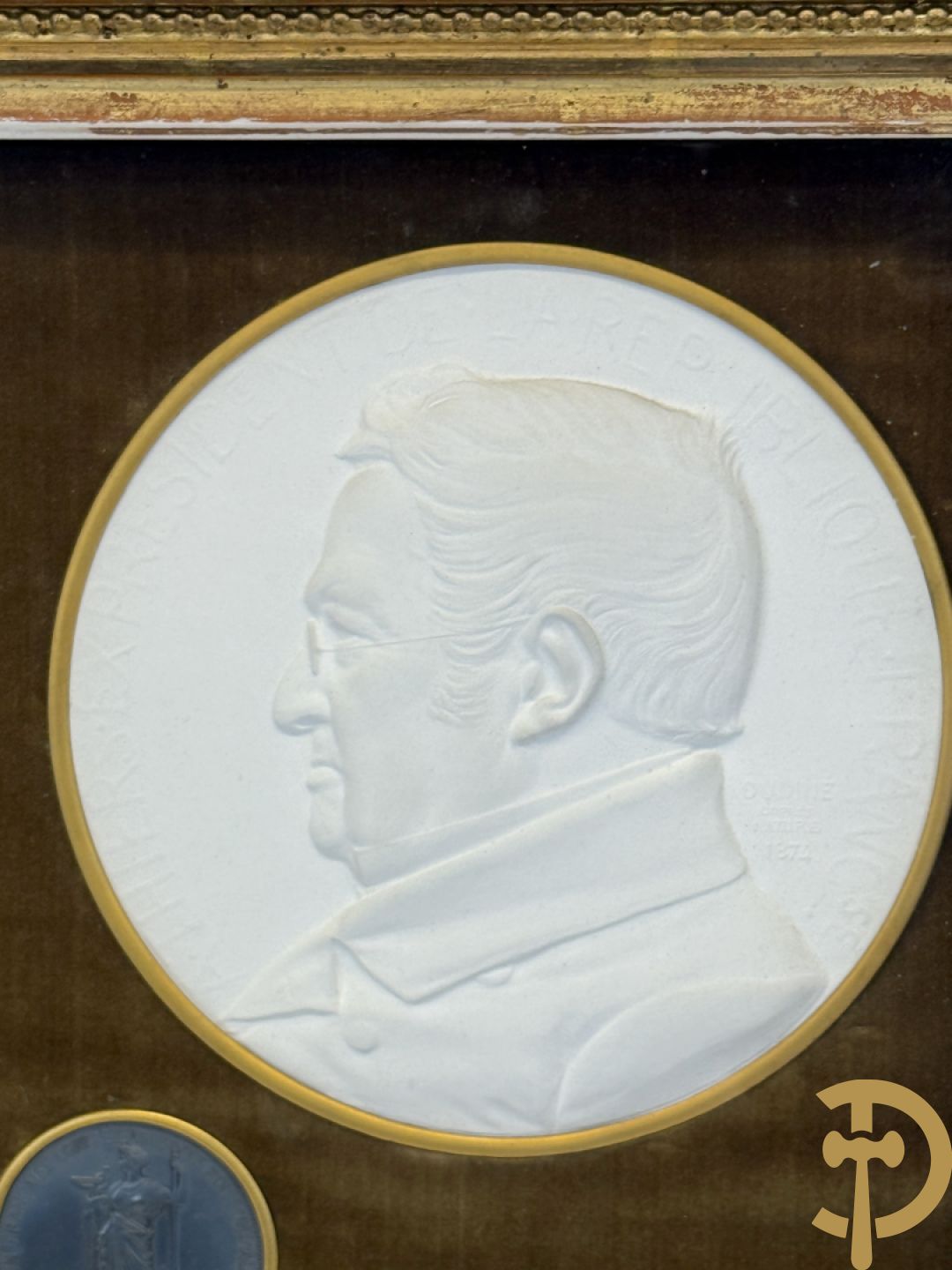 Kader met twee porseleinen plakkettes en 3 munten van Oudiné Eugène André