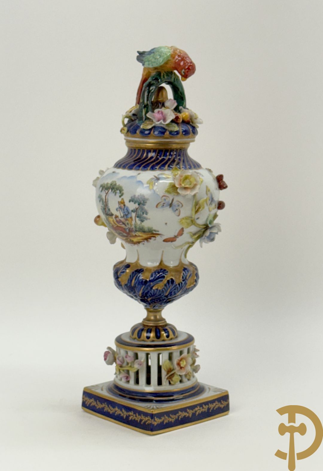 Porseleinen siervaas met handbeschilderd geanimeerd decor bezet met basrelief van bloemen en bovenaan bekroond met deksel met vogel