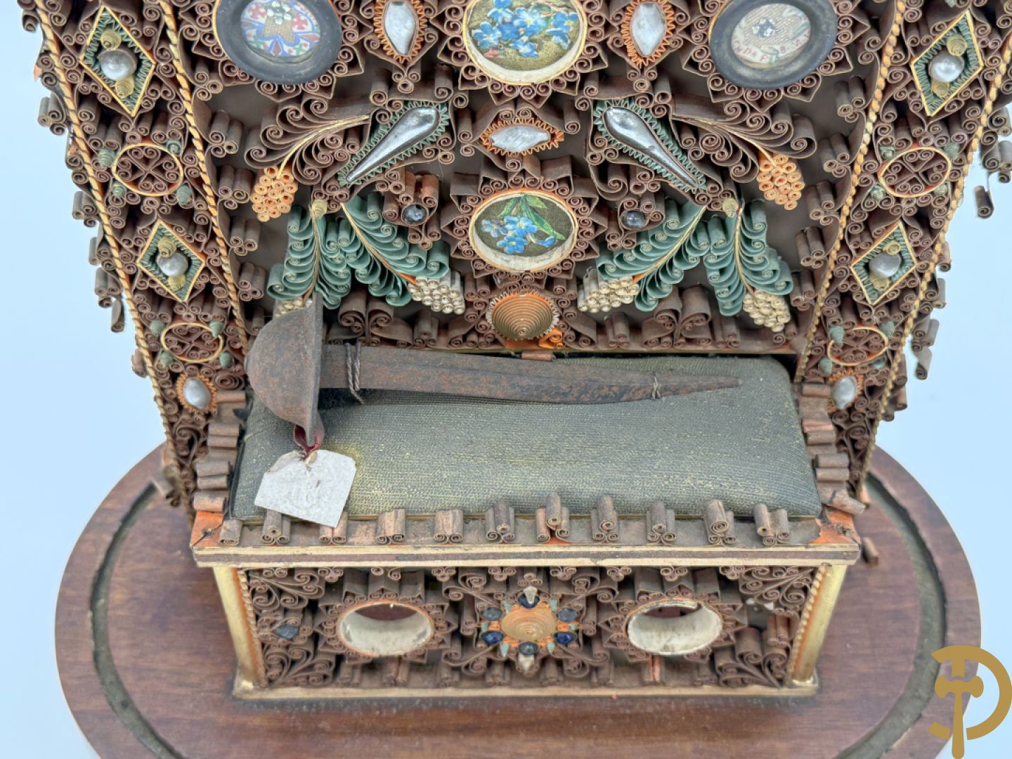 Relikwiehouder in de vorm van een altaar met Christusnagel en omgeven door papperollen - onder stolp