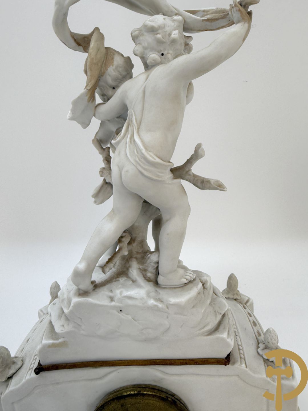 Driedelige porseleinen garnituur bestaande uit pendule bezet met lieftallig koppel, geflankeerd door paar kandelaars met cupido