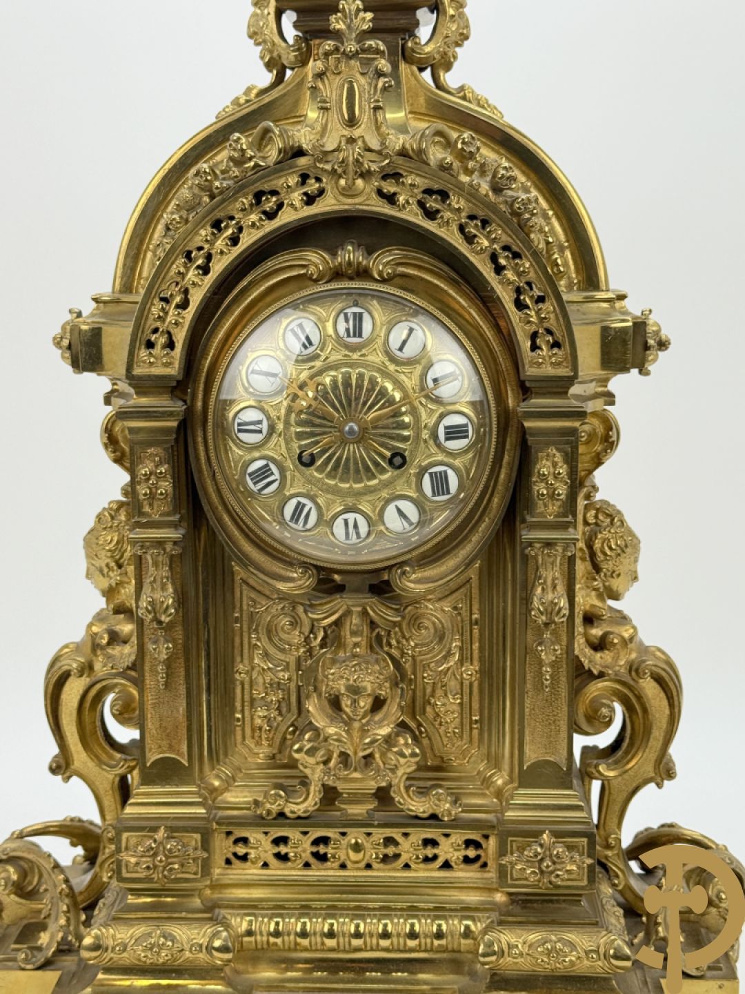 Vuurvergulde bronzen pendule, zijdelings bezet met gevleugelde dames, bovenaan met amfoor