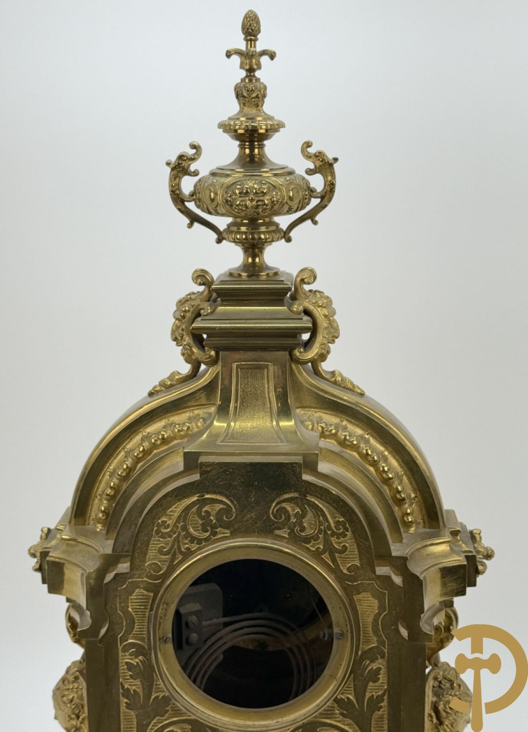 Vuurvergulde bronzen pendule, zijdelings bezet met gevleugelde dames, bovenaan met amfoor