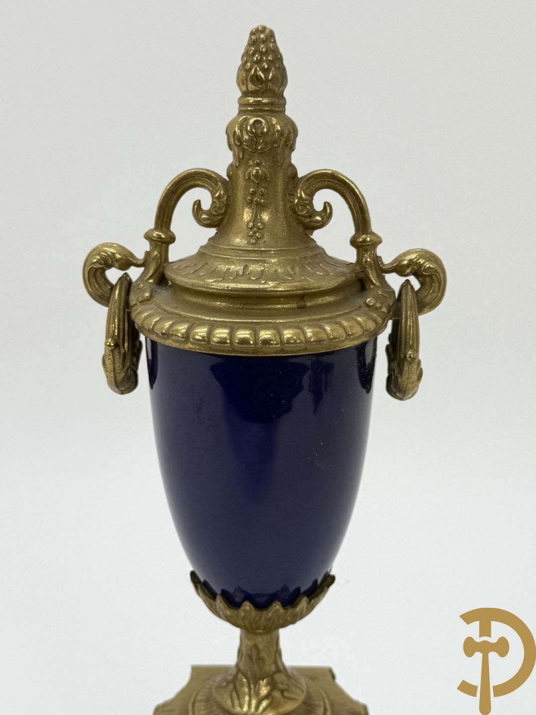 Driedelige koperen garnituur bestaande uit pendule met beschilderd romantisch tafereel en amfoor, zijdelings bezet met paar cassolettes met geanimeerde scènes, onleesbaar getekend rechts onder klok