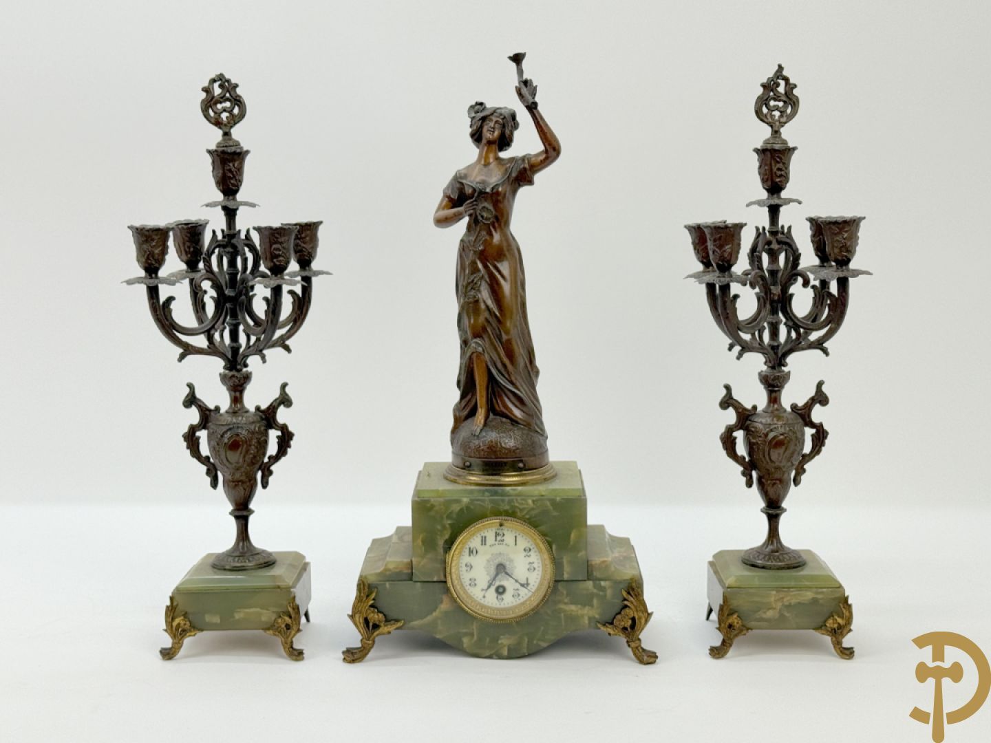 Driedelige zamak garnituur met dame Pavot met bloemen op uurwerk, Rucho getekend, geflankeerd door paar kandelaars