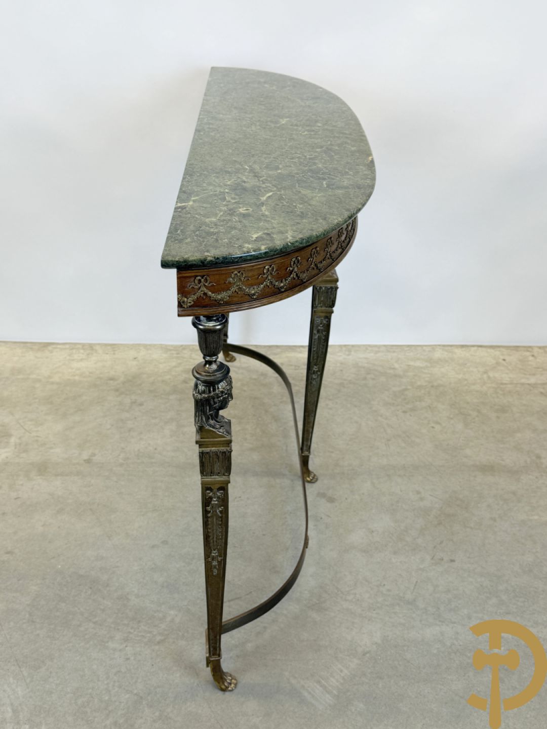 Console op bronzen poten met dameshoofden bezet, bovenaan met groen marmeren blad