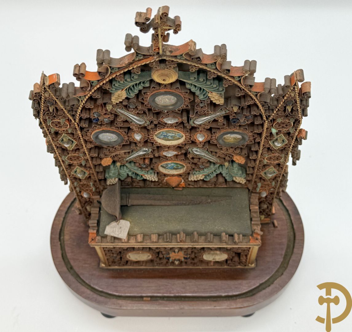 Relikwiehouder in de vorm van een altaar met Christusnagel en omgeven door papperollen - onder stolp