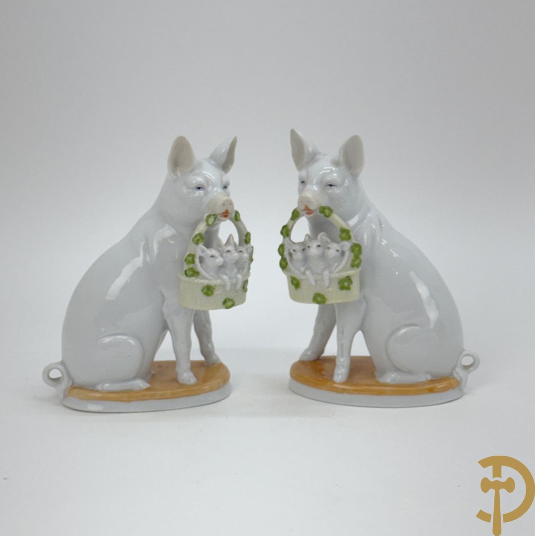 Koppel porseleinen beeldjes met varkens houdende een mandje met biggetjes