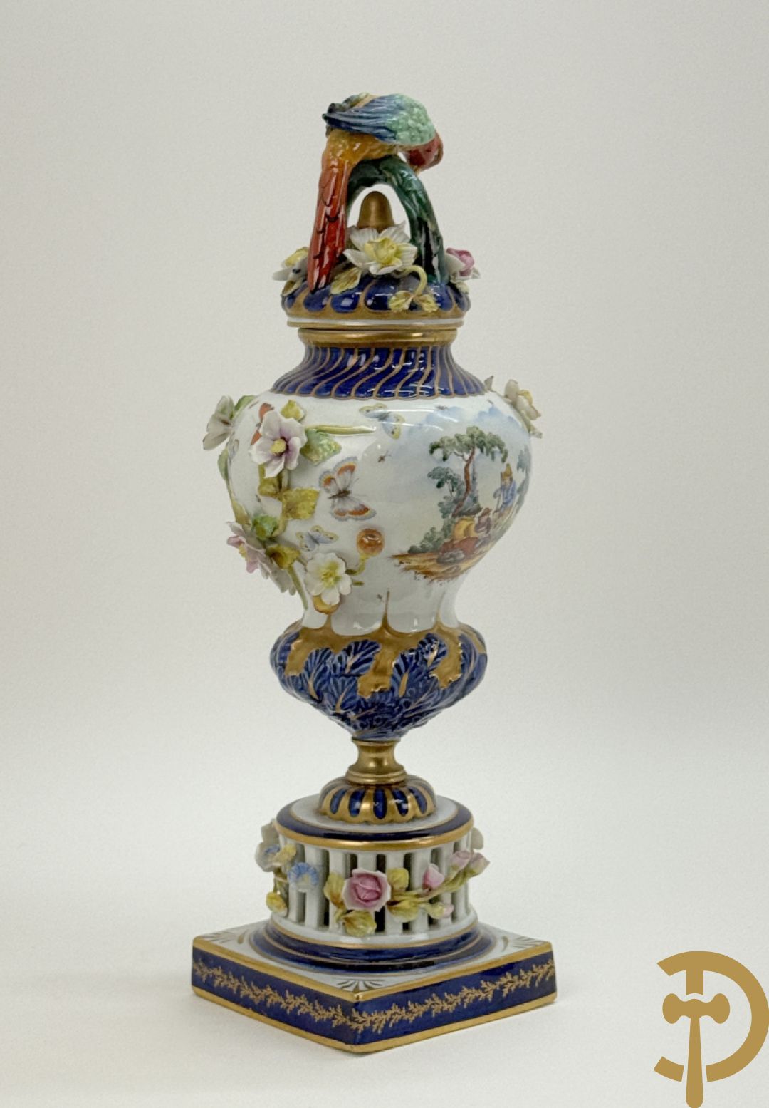 Porseleinen siervaas met handbeschilderd geanimeerd decor bezet met basrelief van bloemen en bovenaan bekroond met deksel met vogel