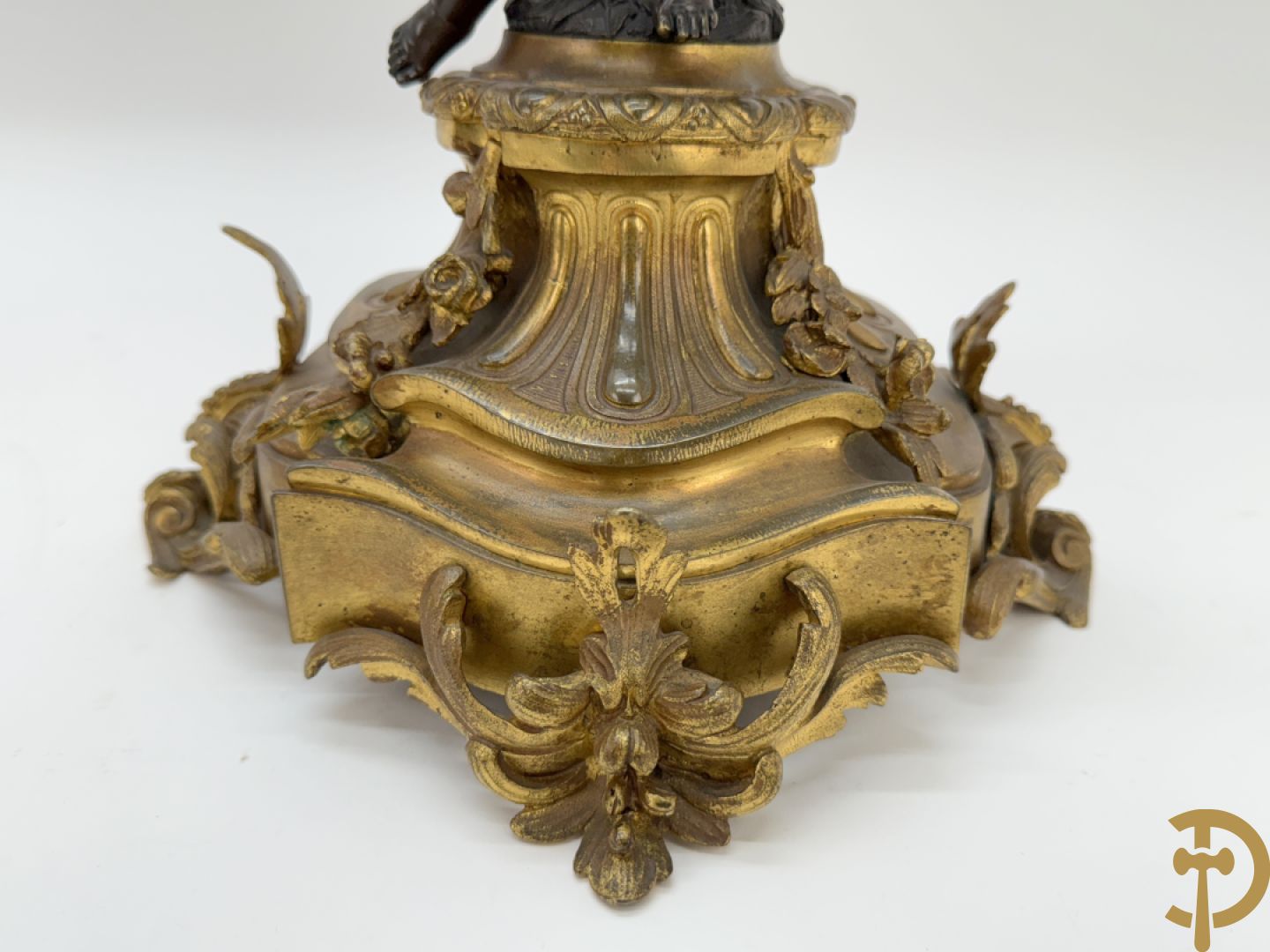 Driedelige bronzen garnituur bestaande uit middenstuk met bronzen vuurvergulde klok, Daubrée gemerkt à Nancy, bovenaan bekroond met Cleopatra met drinkbeker - getekend van Cumberworth sculpteur - geflankeerd door paar cupido