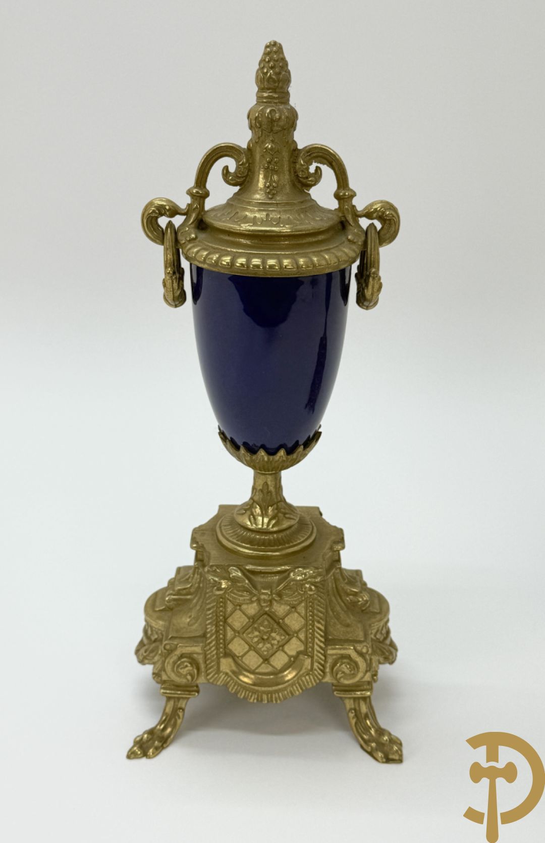 Driedelige koperen garnituur bestaande uit pendule met beschilderd romantisch tafereel en amfoor, zijdelings bezet met paar cassolettes met geanimeerde scènes, onleesbaar getekend rechts onder klok