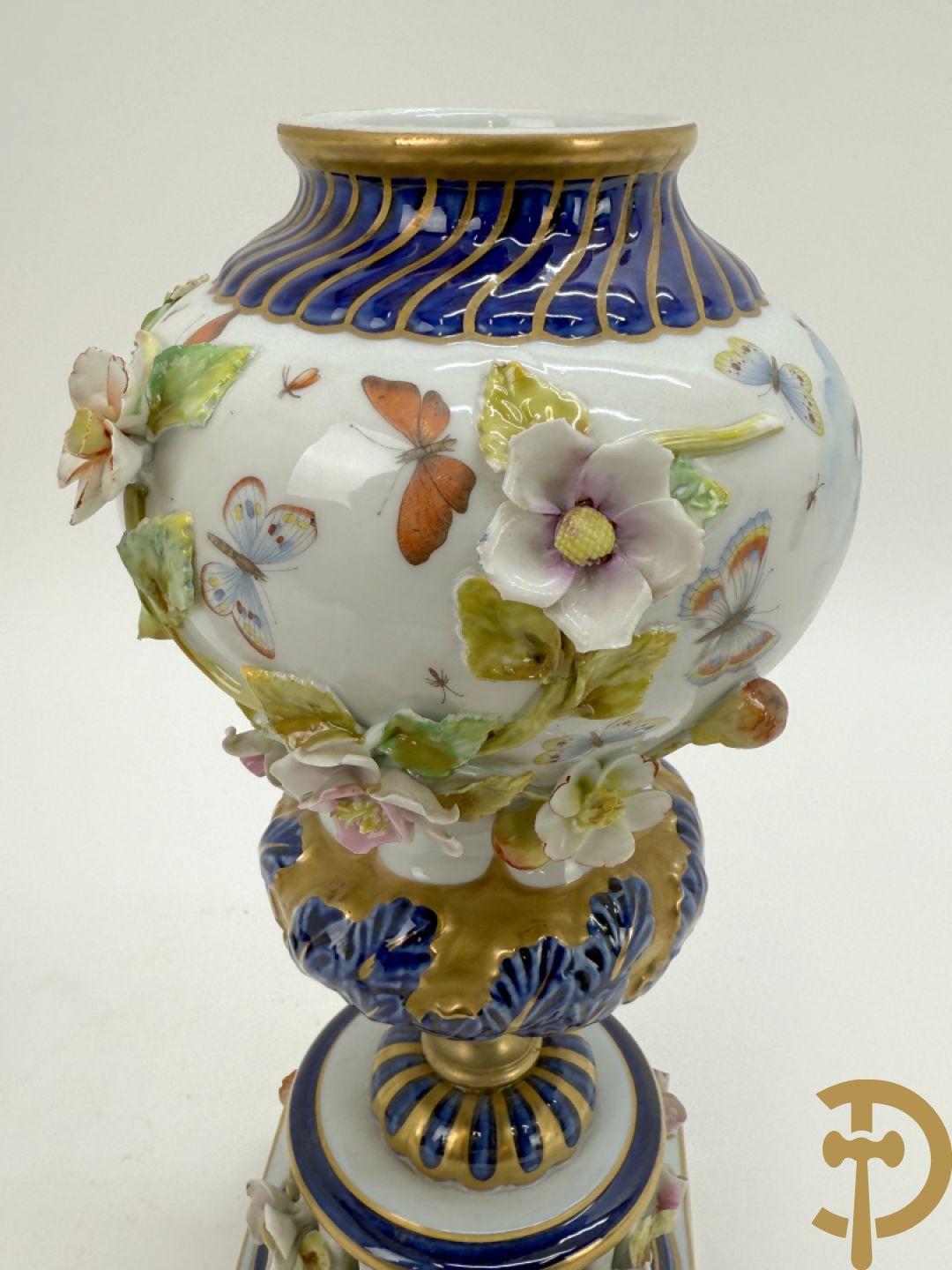 Porseleinen siervaas met handbeschilderd geanimeerd decor bezet met basrelief van bloemen en bovenaan bekroond met deksel met vogel