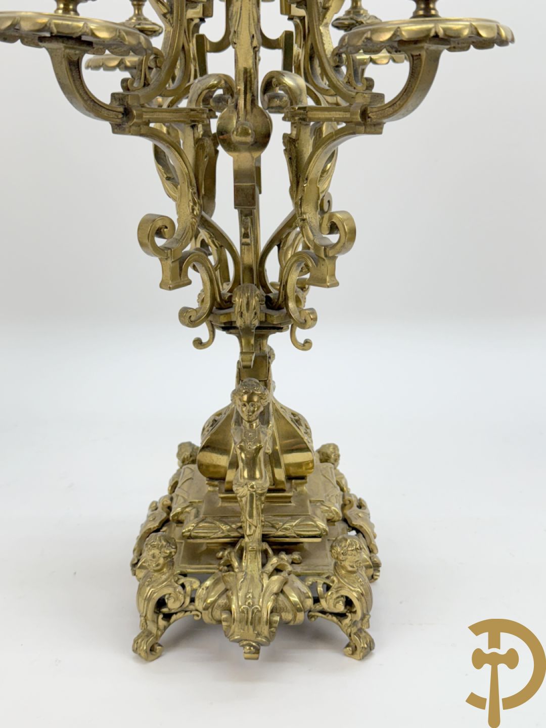 Driedelige bronzen vergulde garntiuur bestaande uit klok met medusahoofden en sfinxen, geflankeerd door paar zevenarmige kandelaars met accanthusranken en sfinxen