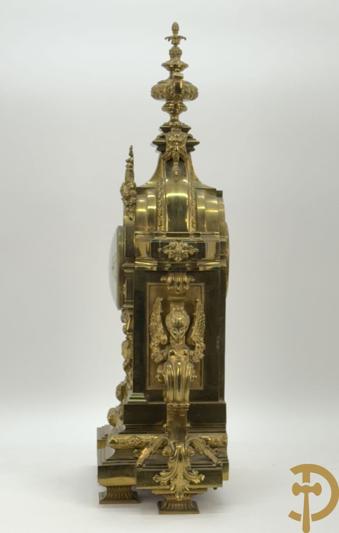 Vuurvergulde bronzen pendule, zijdelings bezet met gevleugelde dames, bovenaan met amfoor