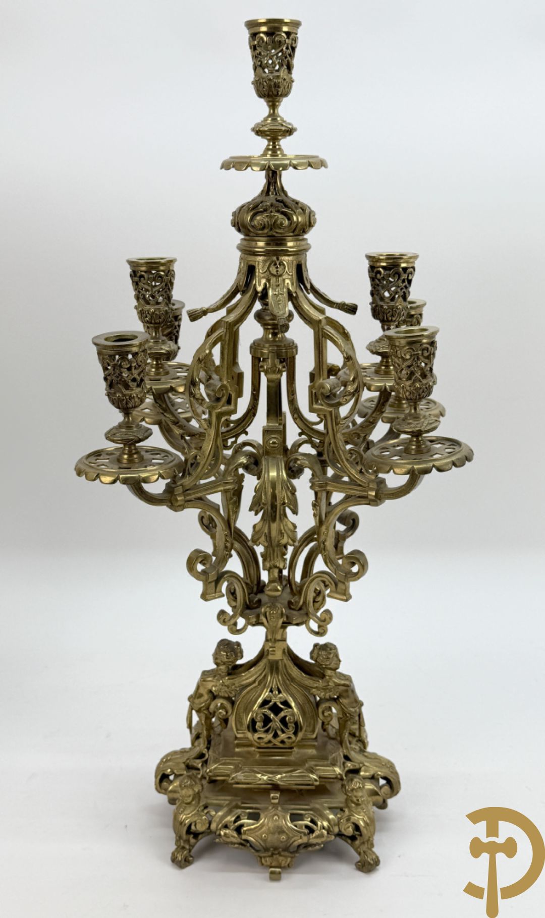 Driedelige bronzen vergulde garntiuur bestaande uit klok met medusahoofden en sfinxen, geflankeerd door paar zevenarmige kandelaars met accanthusranken en sfinxen