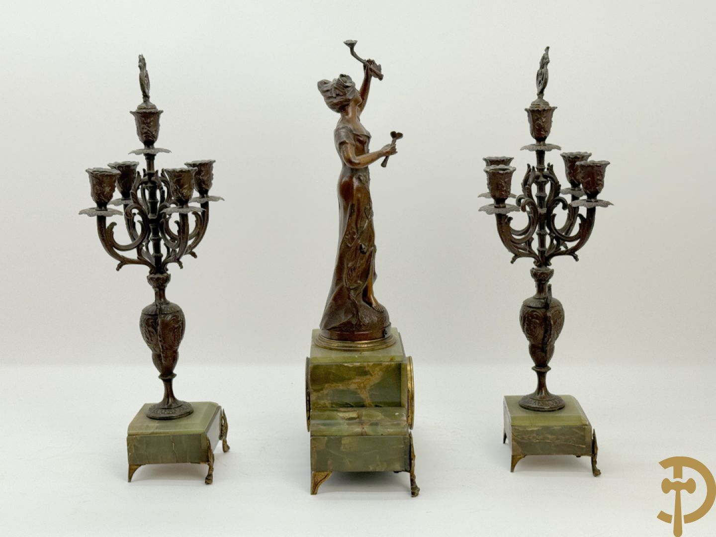 Driedelige zamak garnituur met dame Pavot met bloemen op uurwerk, Rucho getekend, geflankeerd door paar kandelaars