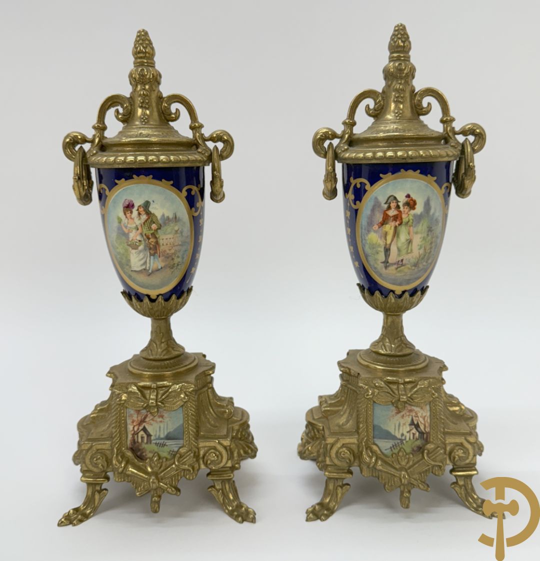 Driedelige koperen garnituur bestaande uit pendule met beschilderd romantisch tafereel en amfoor, zijdelings bezet met paar cassolettes met geanimeerde scènes, onleesbaar getekend rechts onder klok