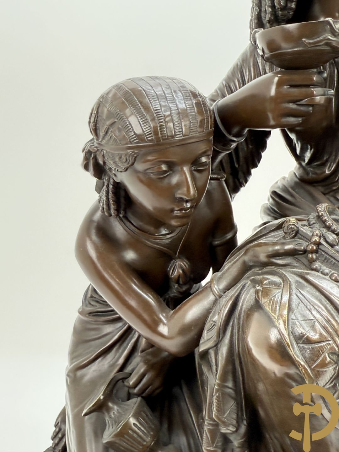 Driedelige bronzen garnituur bestaande uit middenstuk met bronzen vuurvergulde klok, Daubrée gemerkt à Nancy, bovenaan bekroond met Cleopatra met drinkbeker - getekend van Cumberworth sculpteur - geflankeerd door paar cupido
