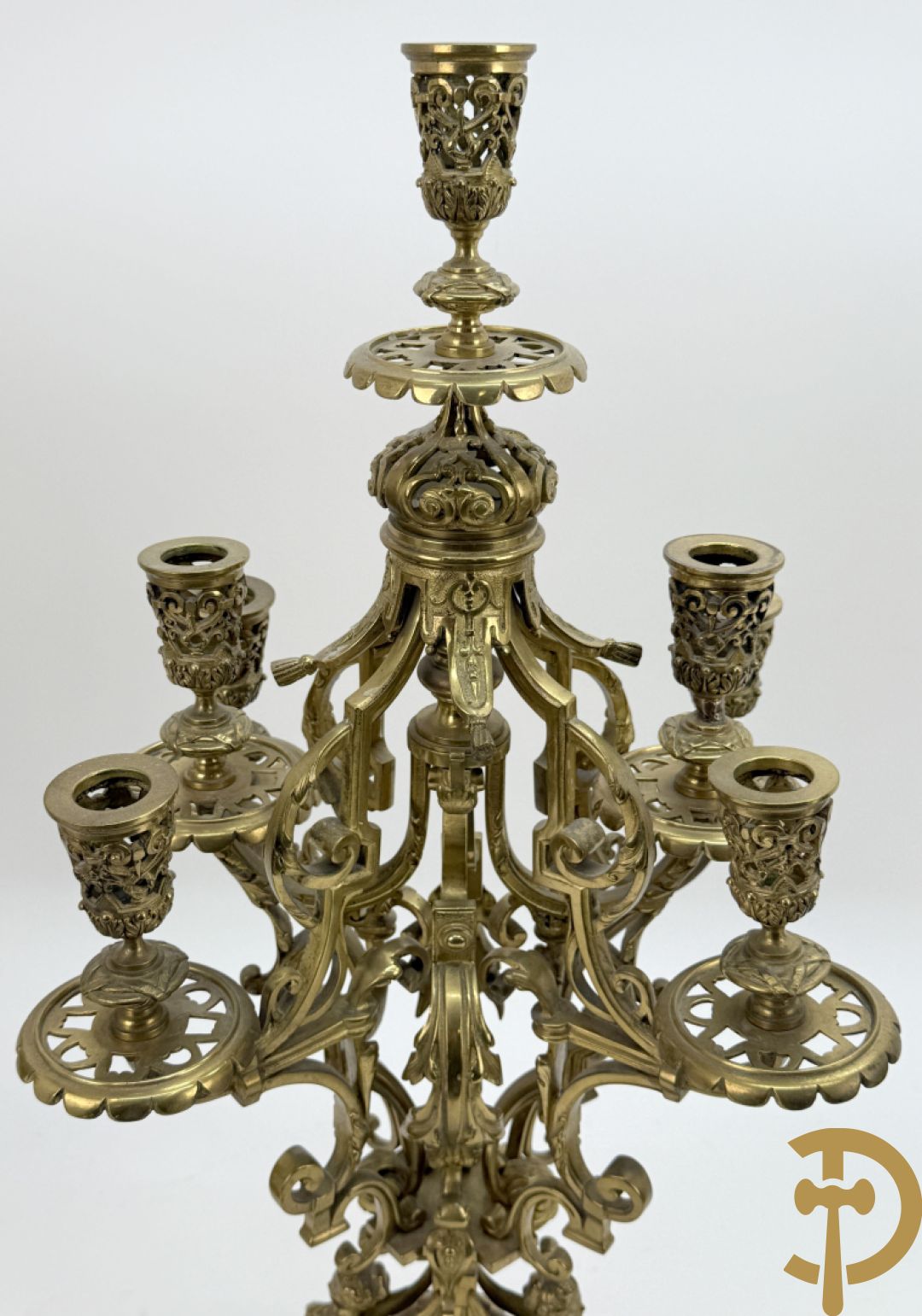 Driedelige bronzen vergulde garntiuur bestaande uit klok met medusahoofden en sfinxen, geflankeerd door paar zevenarmige kandelaars met accanthusranken en sfinxen