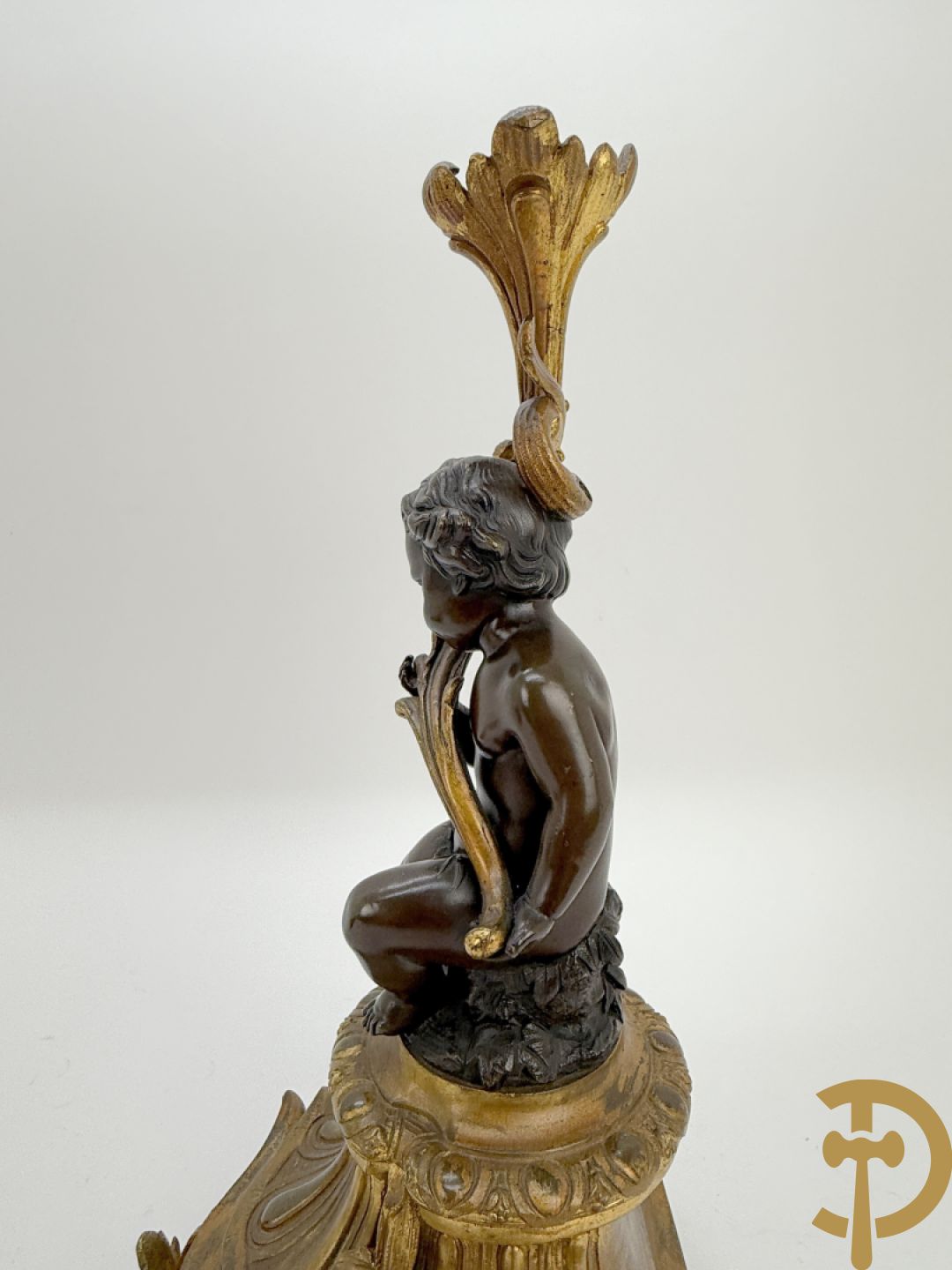 Driedelige bronzen garnituur bestaande uit middenstuk met bronzen vuurvergulde klok, Daubrée gemerkt à Nancy, bovenaan bekroond met Cleopatra met drinkbeker - getekend van Cumberworth sculpteur - geflankeerd door paar cupido