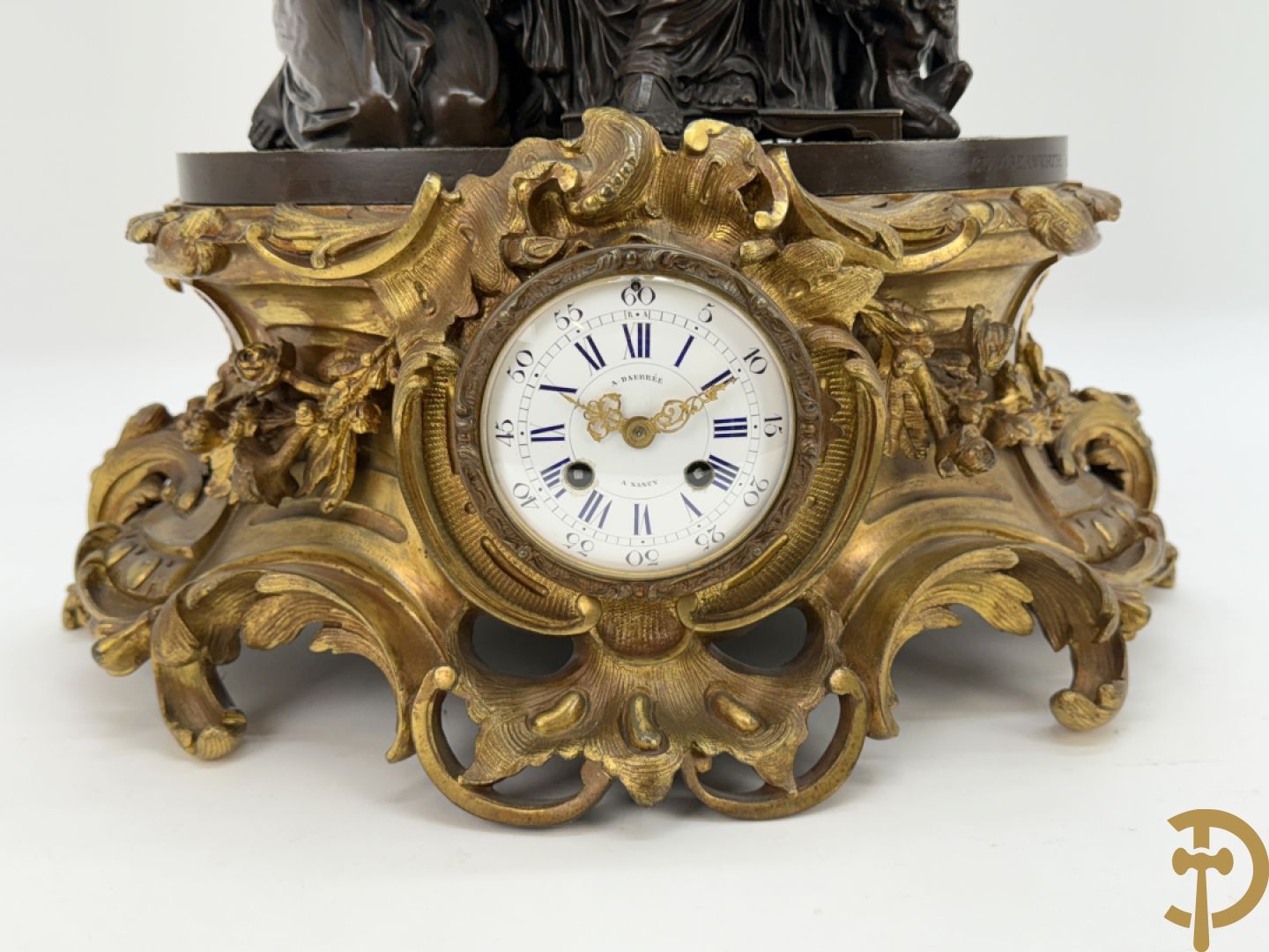 Driedelige bronzen garnituur bestaande uit middenstuk met bronzen vuurvergulde klok, Daubrée gemerkt à Nancy, bovenaan bekroond met Cleopatra met drinkbeker - getekend van Cumberworth sculpteur - geflankeerd door paar cupido