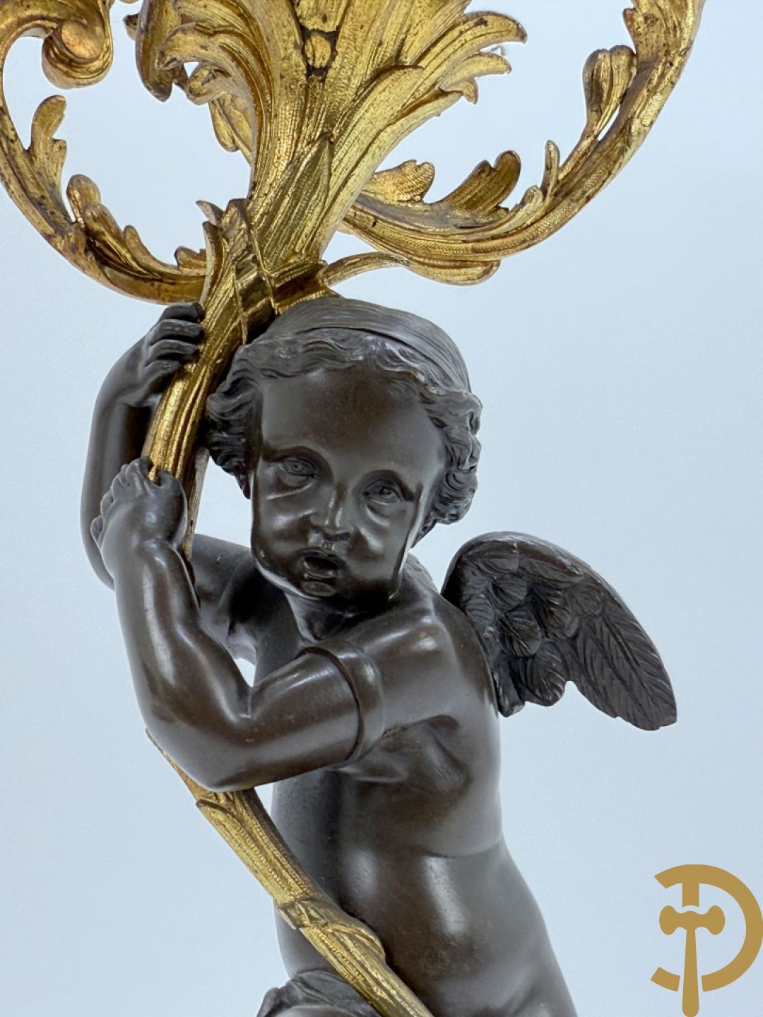 Bronzen cupido dragende een zevenarmige kandelaar