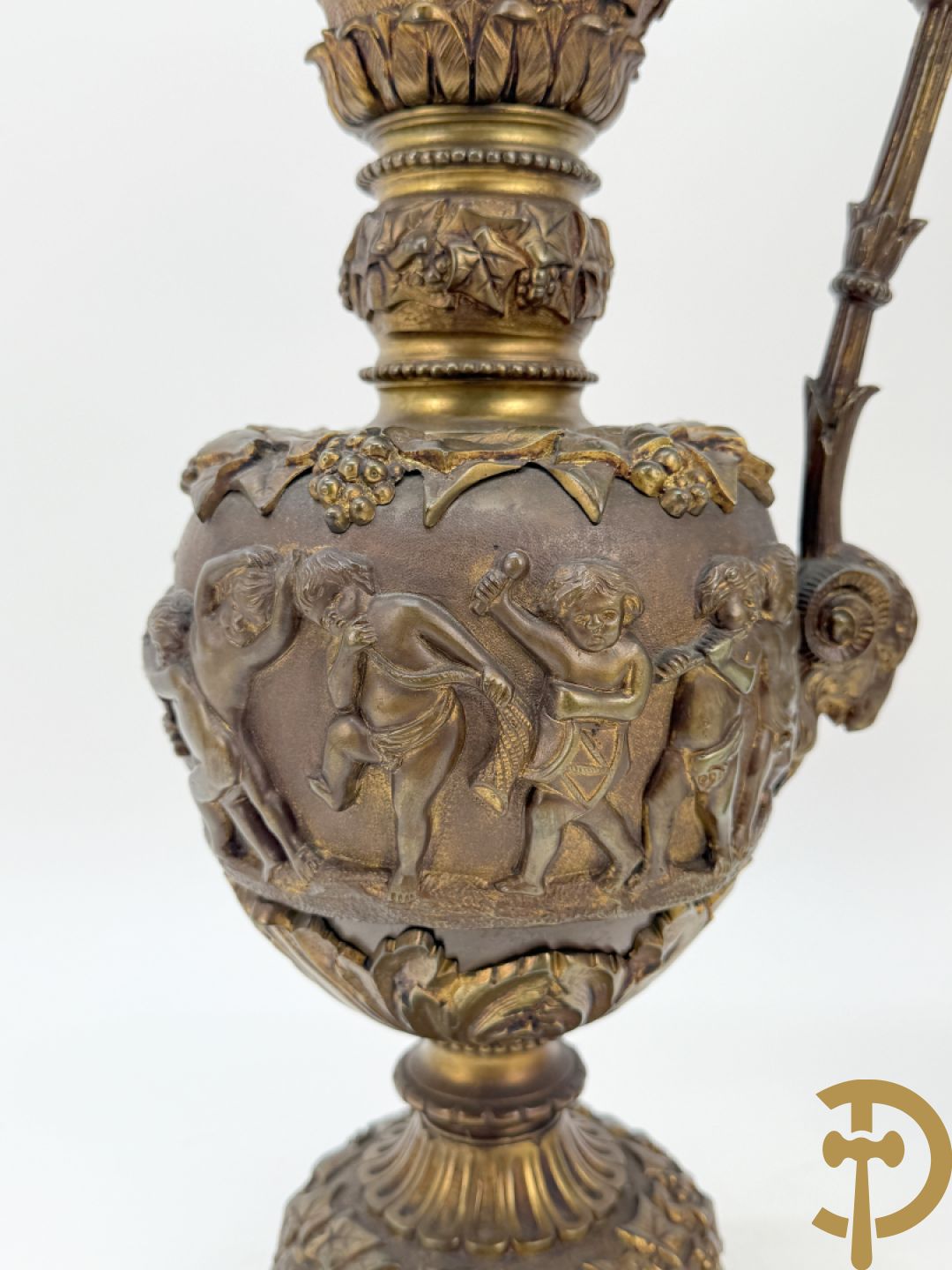 Paar bronzen schenkkannen met basrelief van putti en accanthusranken
