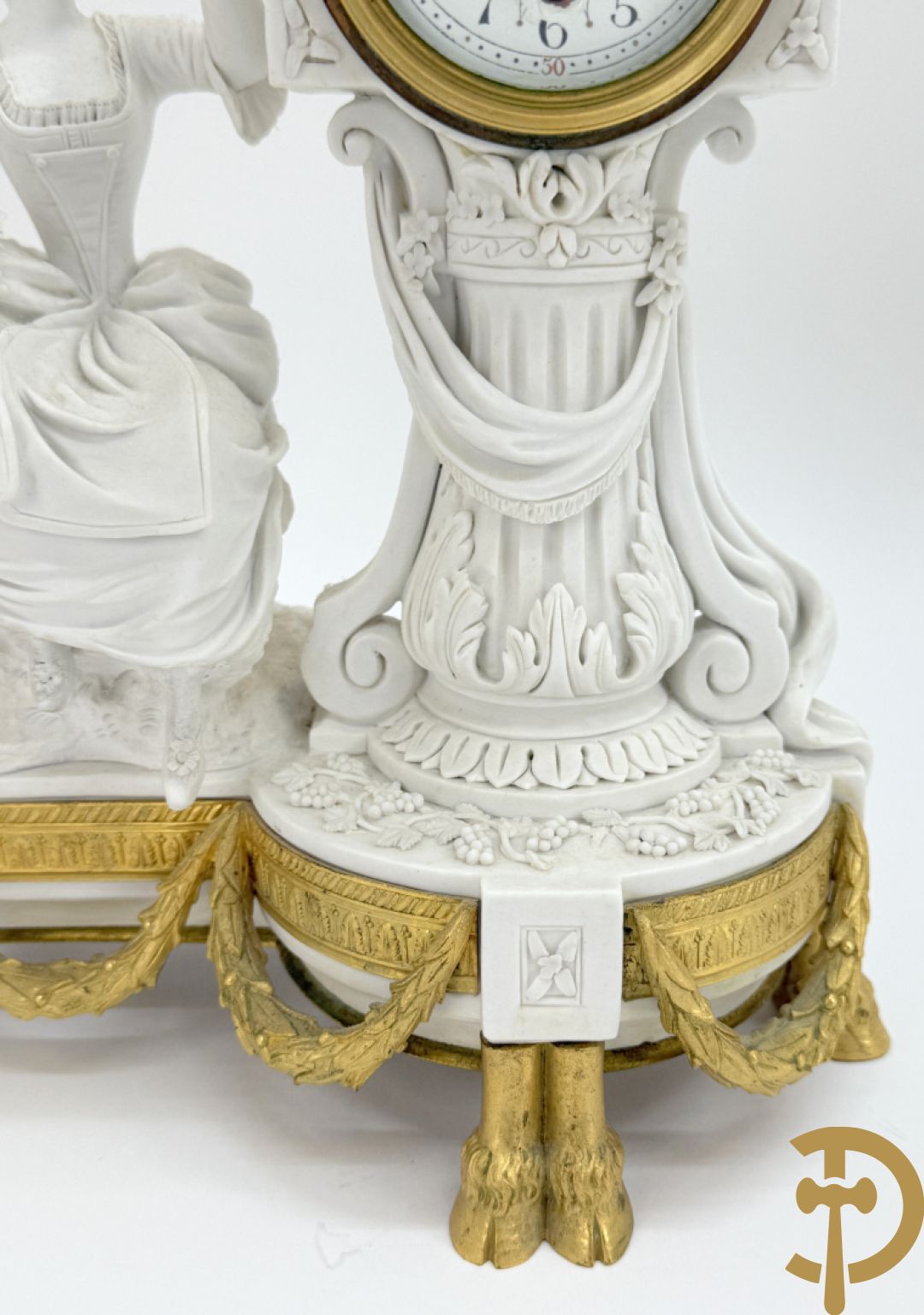 Driedelige porseleinen garnituur met bronsbeslag bestaande uit pendule met dame en amfoor geflankeerd door paar kandelaars bezet met personages